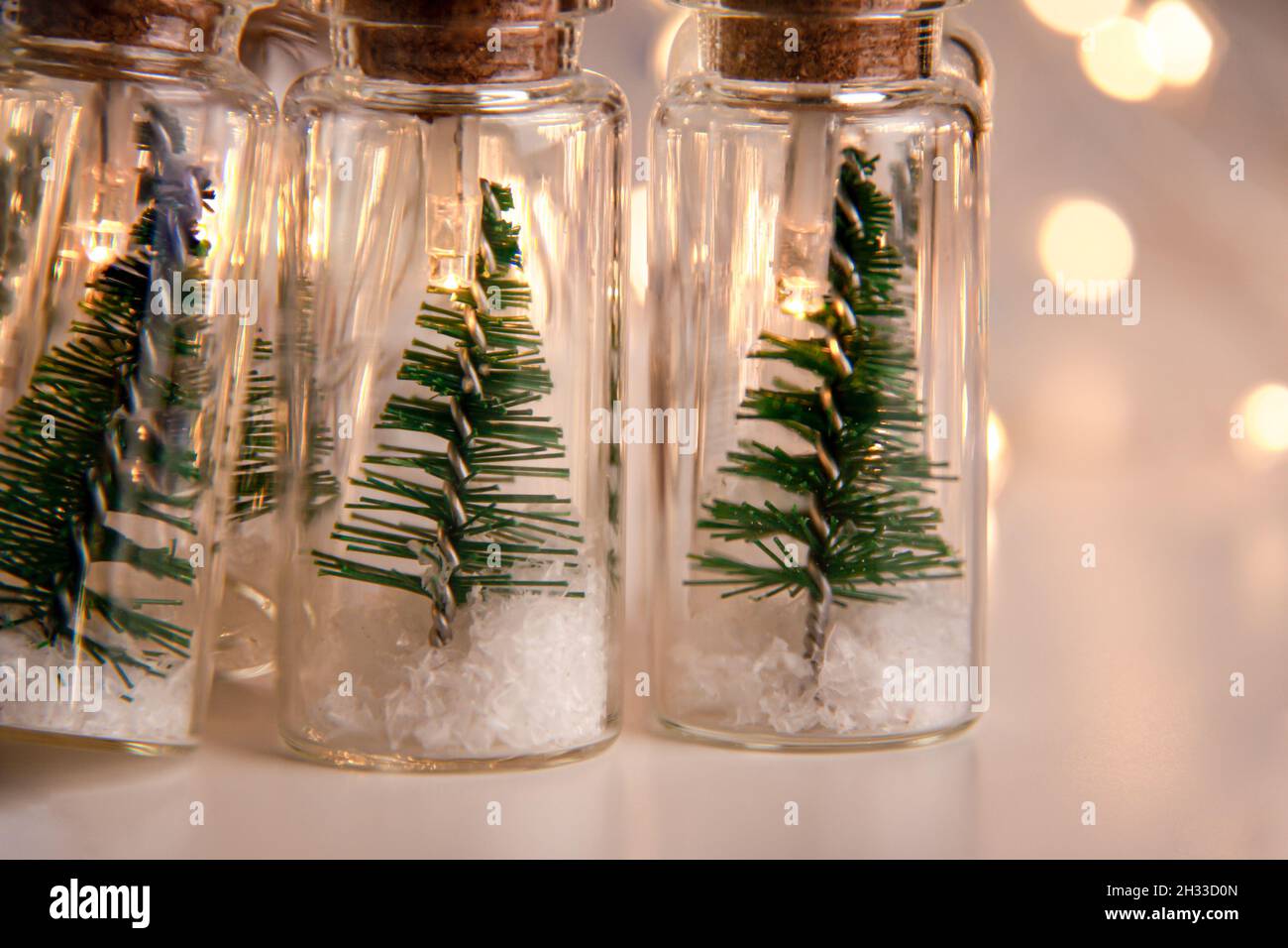 Primo piano di luci incandescenti decorazione di vasi di vetro con tappi  all'interno dei quali ci sono piccoli alberi verdi di Natale su neve  artificiale. Vacanze nuovo Yea Foto stock - Alamy