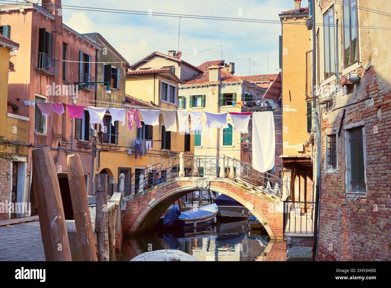 Linee di lavaggio attraverso il canale di Venezia, Italia. Lavanderia appesa su una linea di abbigliamento tra gli edifici della città e sopra il ponte. Linee di abbigliamento tra le finestre Foto Stock