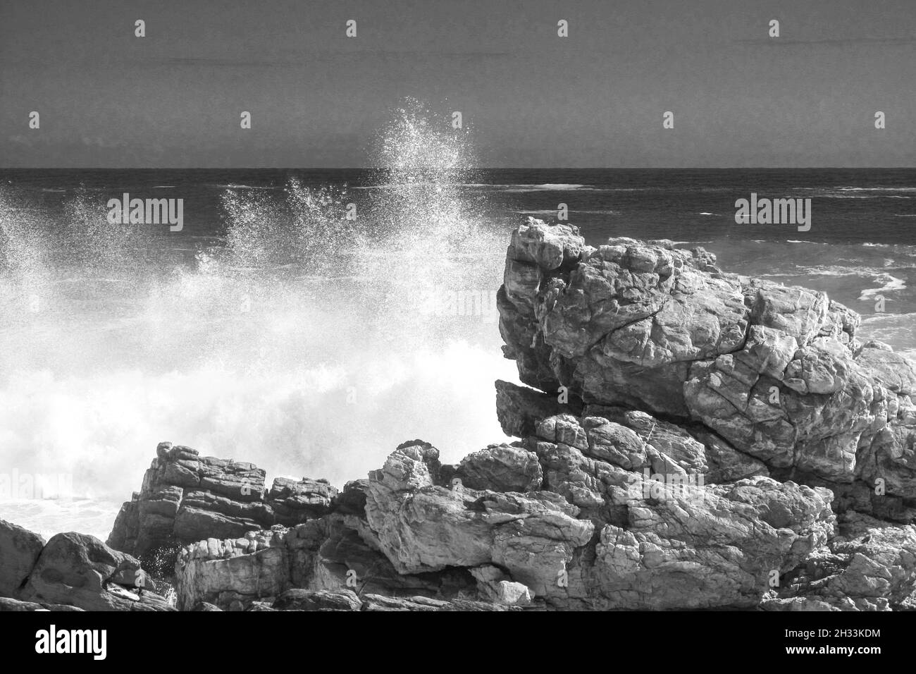Spruzzi dalle onde forti in bianco e nero lungo la costa rocciosa della sezione di Tsitsikamma nel Parco Nazionale del percorso del giardino del Sudafrica Foto Stock
