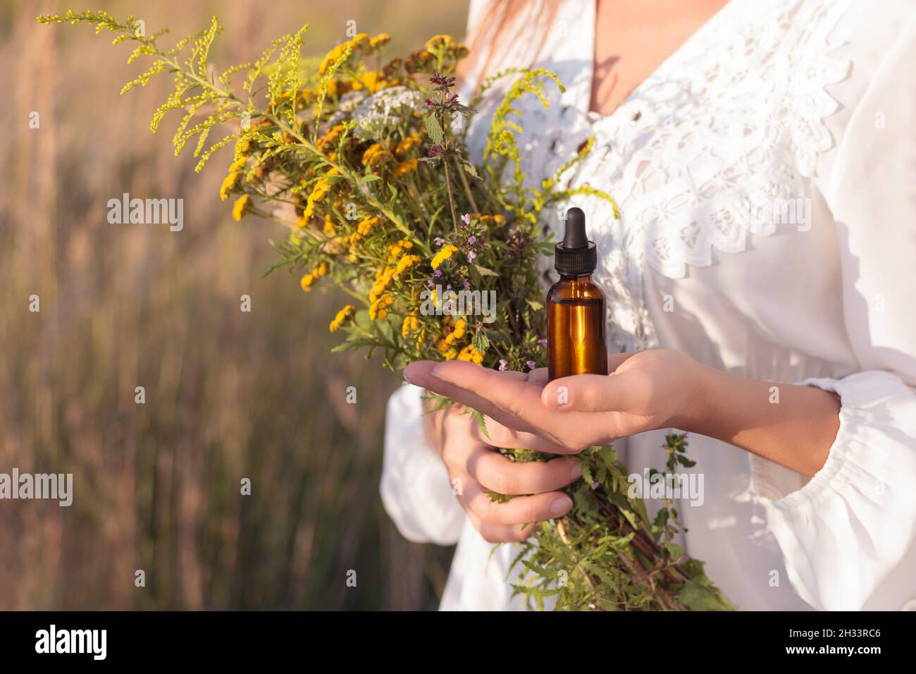 Bottiglia con un contagocce sul palmo della mano - l'erborista raccoglie le erbe. Foto Stock