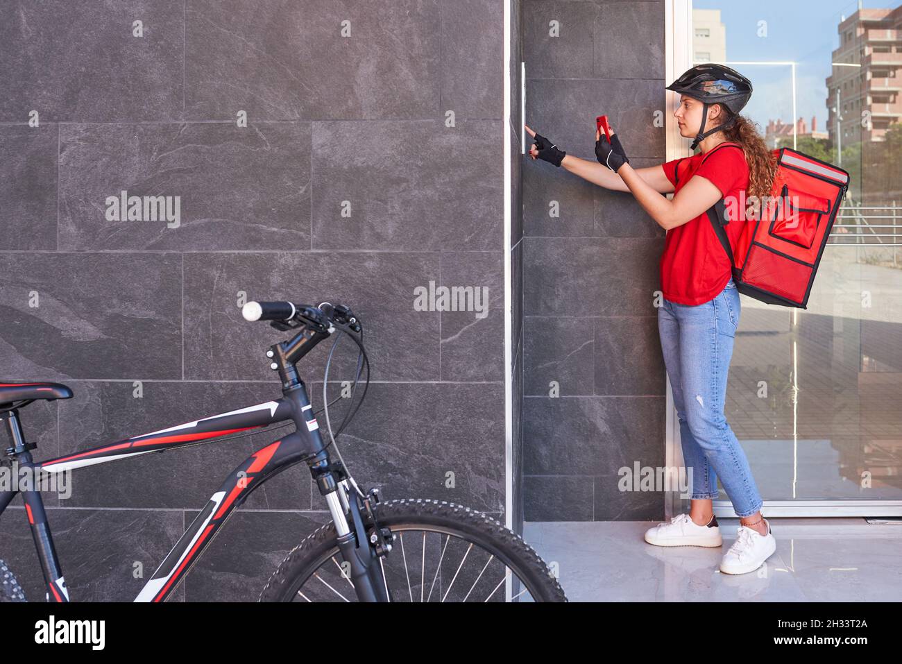 Una ragazza consegna ciclista che suona la campana dell'interfono Foto  stock - Alamy