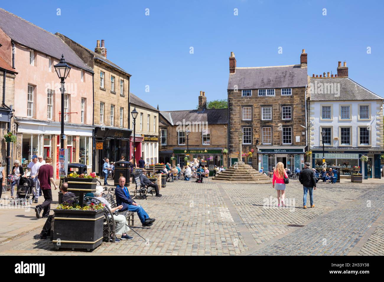 Persone nella storica Piazza del mercato e Market Cross Market Place Alnwick centro città Alnwick Northumberland Northumbria Inghilterra Regno Unito GB Europa Foto Stock