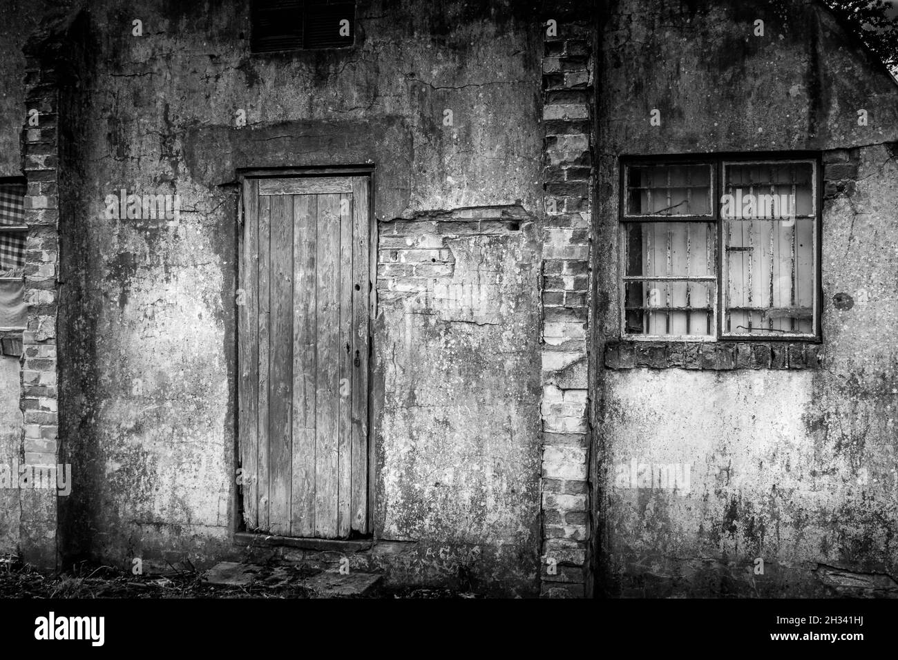 Vista posteriore del vecchio rifugio Nissen utilizzato durante la guerra fredda per ospitare prigionieri militari, mostrando finestra con bar originali e vecchia porta di legno. Nessuna gente Foto Stock