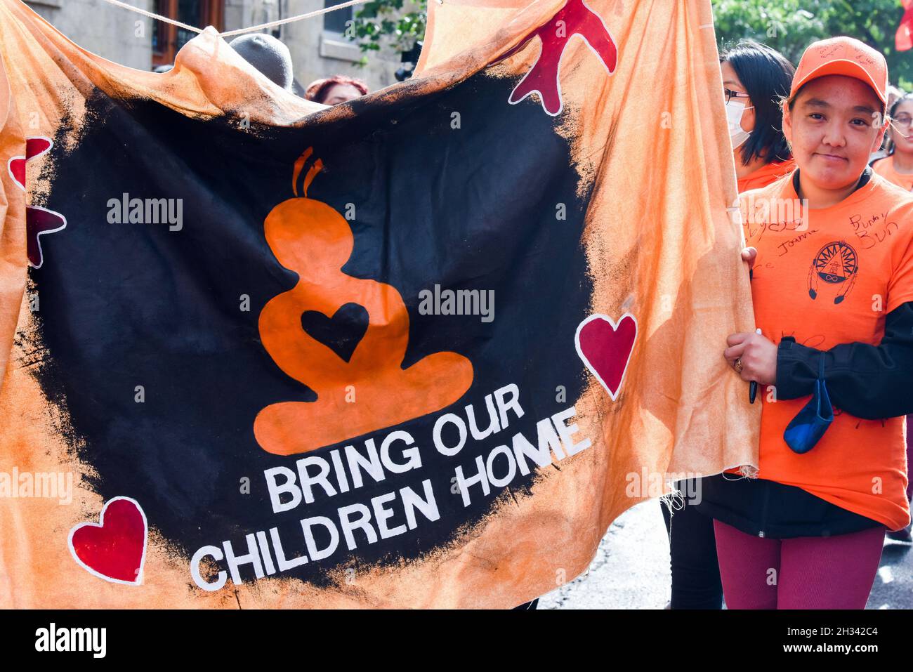 Questo poster durante la protesta del 'Orange Shirt Day' a Montreal si riferisce alle numerose tombe di massa nascoste dei bambini della prima nazione in Canada. Le popolazioni indigene in Canada chiedono al loro governo di fare di più per scoprire tutte le tombe potenziali delle scuole residenziali indiane e che i resti siano portati nella terra ancestrale dei bambini Foto Stock