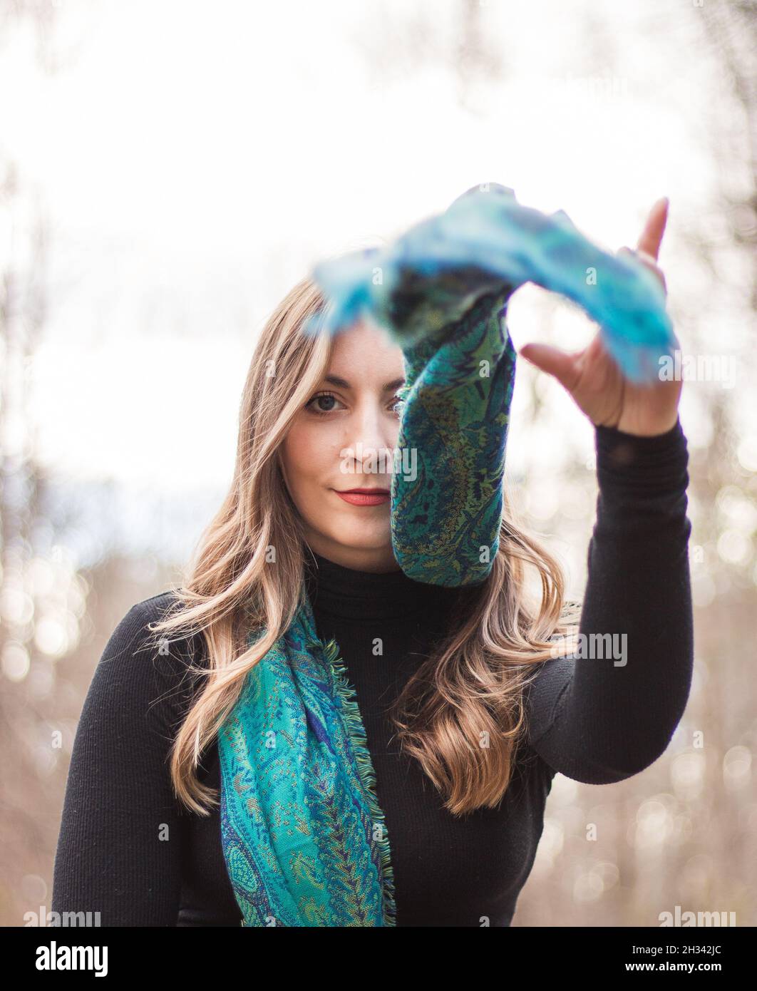 Elegante modello femminile in posa nel bosco godendo la caduta con una sciarpa blu e occhi blu Foto Stock