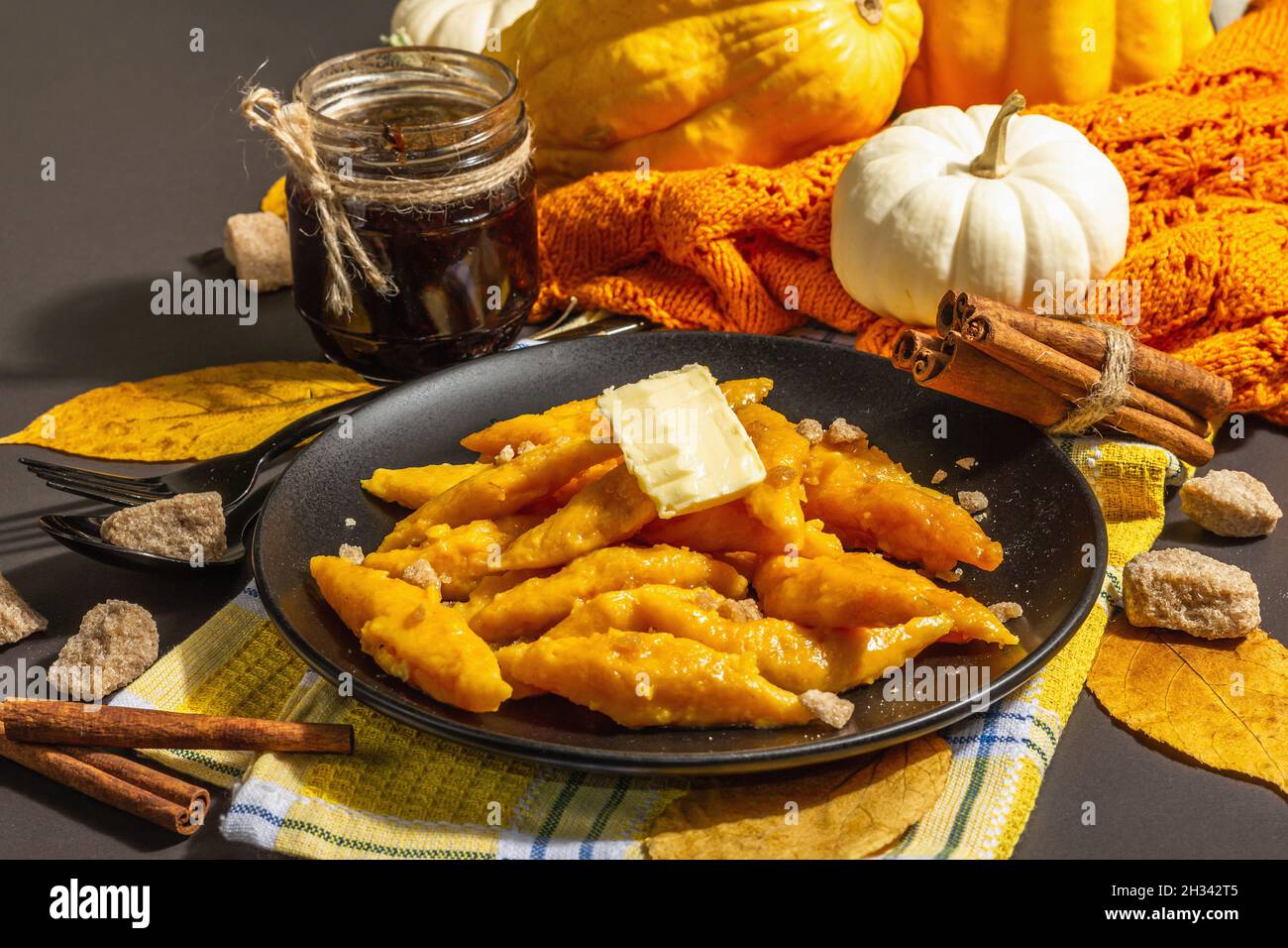 Gnocchi di zucca pigri, gnocchi al burro e zucchero di canna. Piatto caldo d'autunno, cibo dolce e sano. Sfondo in pietra nera, luce dura alla moda, Foto Stock