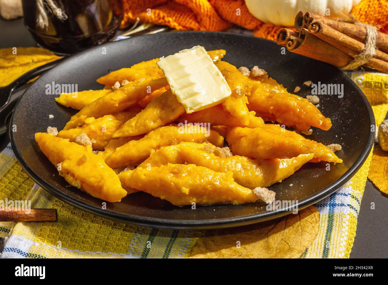 Gnocchi di zucca pigri, gnocchi al burro e zucchero di canna. Piatto caldo d'autunno, cibo dolce e sano. Sfondo in pietra nera, luce dura alla moda, Foto Stock