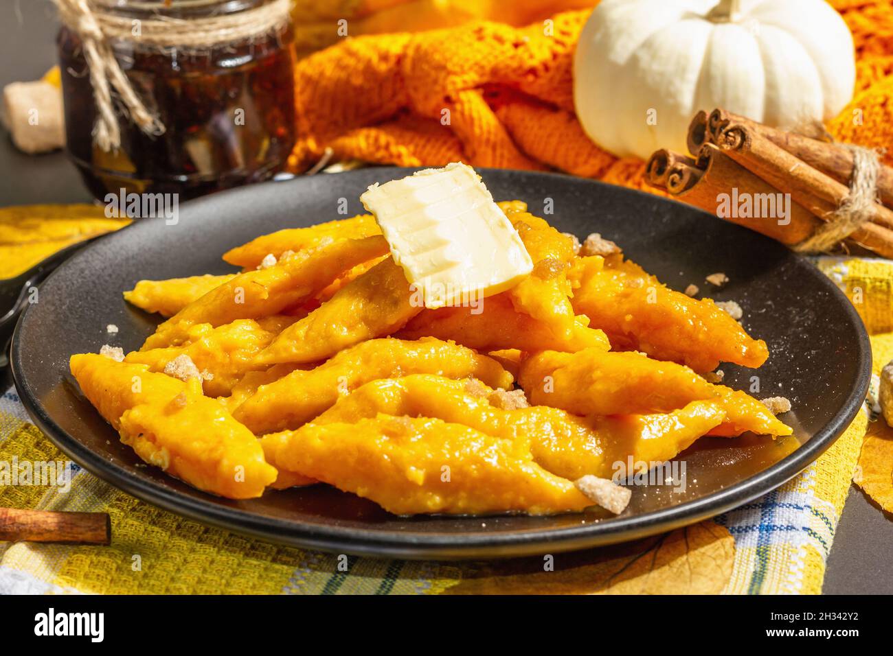 Gnocchi di zucca pigri, gnocchi al burro e zucchero di canna. Piatto caldo d'autunno, cibo dolce e sano. Sfondo in pietra nera, luce dura alla moda, Foto Stock