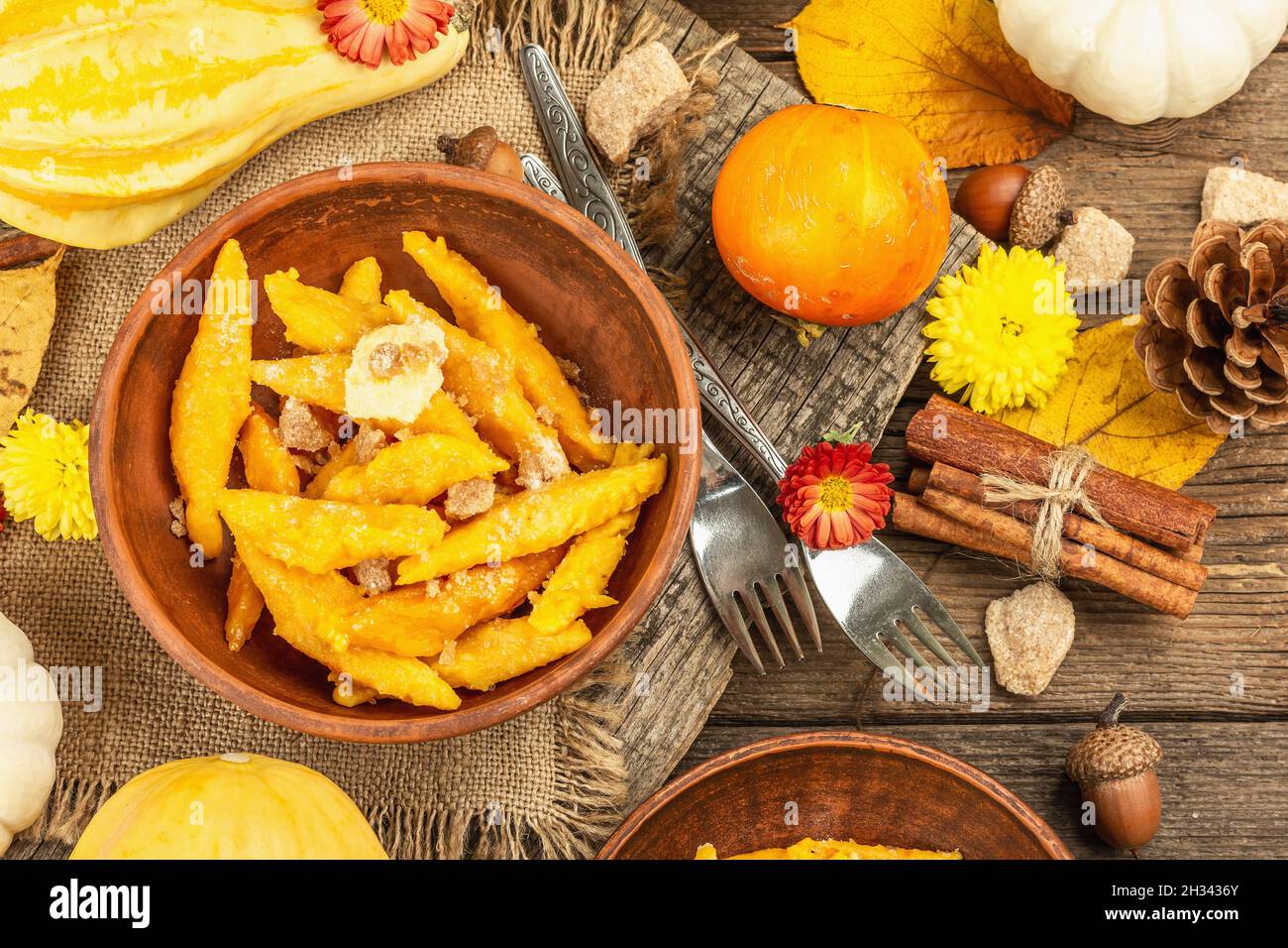 Gnocchi di zucca o gnocchi italiani. Piatto di squash vegetariano sano con formaggio caserario. Decorazioni autunnali con foglie autunnali, coni, zucche intere mature, f Foto Stock