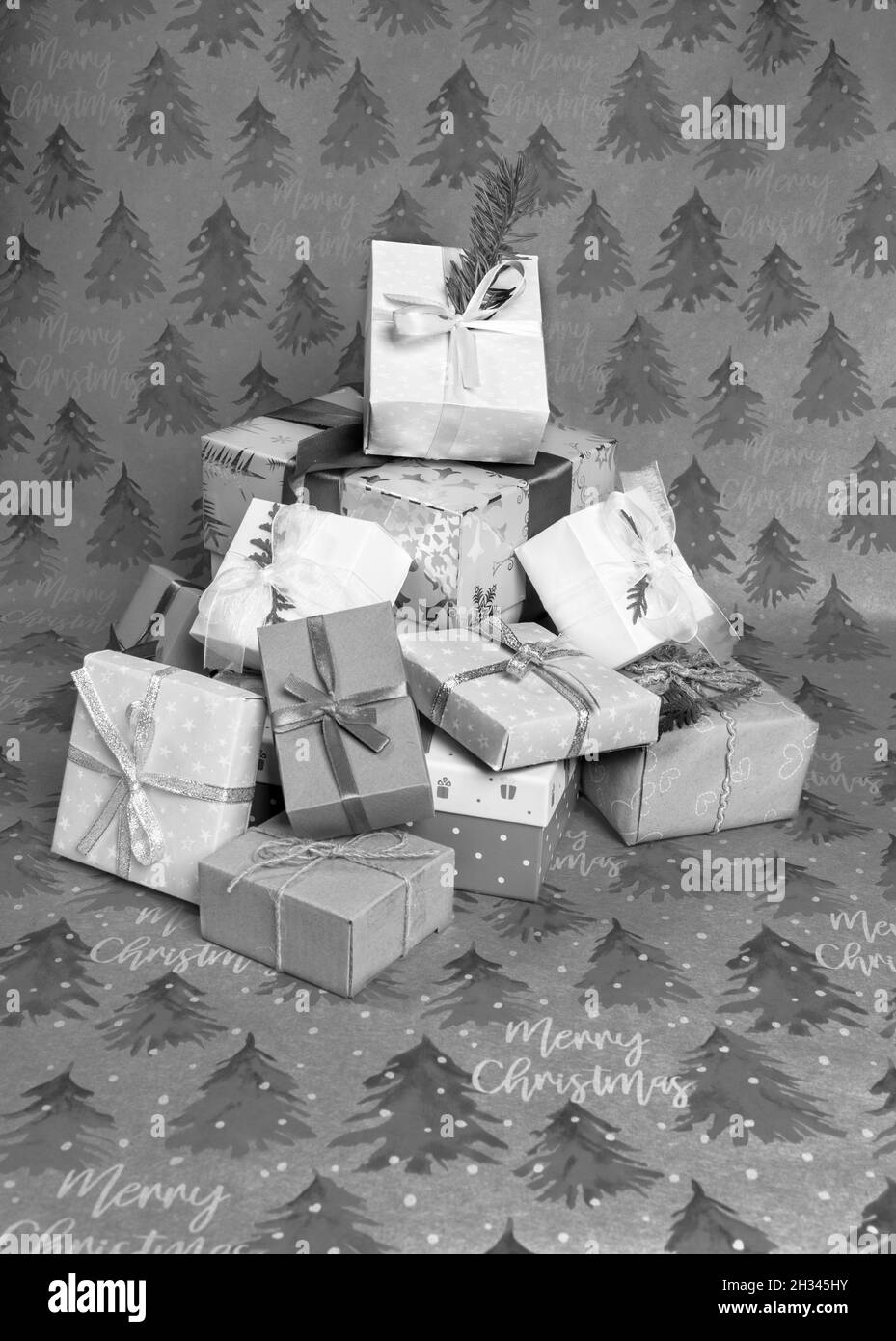Mucchio di Natale scatole regalo decorate a mano di varie forme e dimensioni su carte da imballaggio festive con spruces e iscrizioni Buon Natale. Natale holi Foto Stock