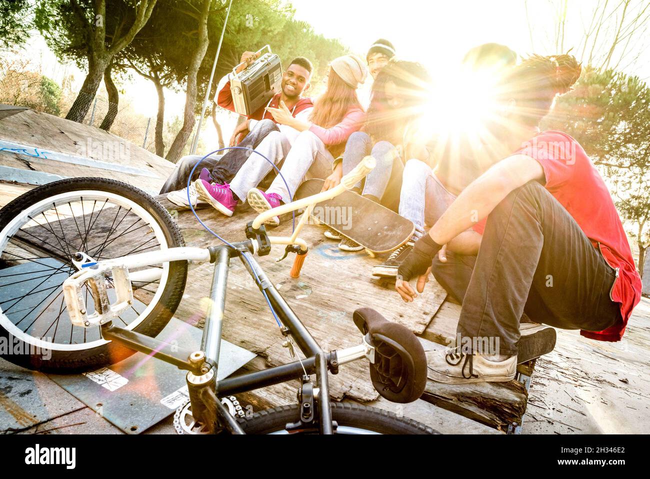 Gruppo di amici alla moda che si divertono insieme al parco skate bmx - concetto di amicizia giovanile con i giovani all'aperto - Focus su ragazzo afroamericano Foto Stock