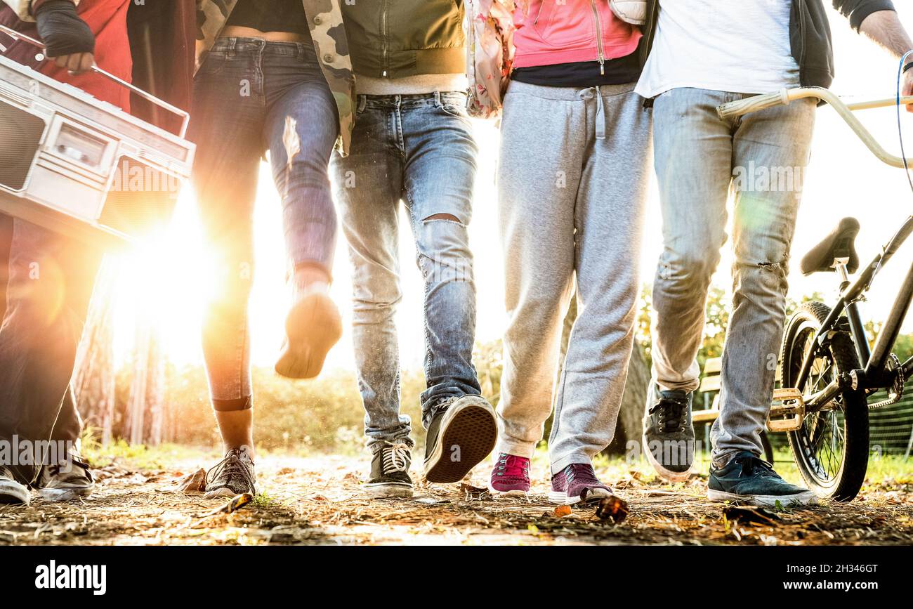 Amici che camminano nel parco cittadino con retroilluminazione e sunflare Halo - concetto di amicizia Milleniale e giovani multirazziali Foto Stock
