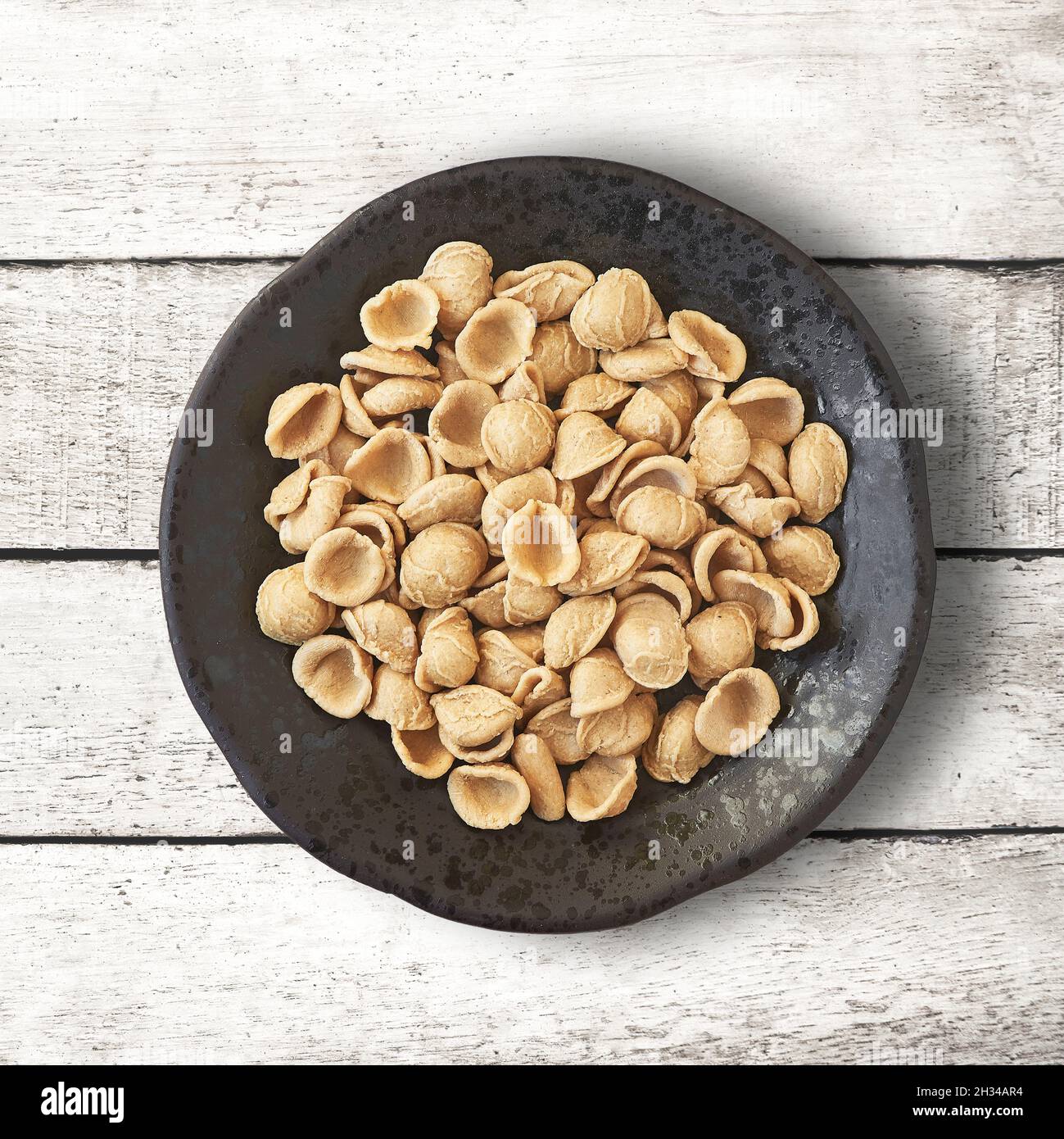 Orecchiette d'orzo pugliese su un recipiente rustico. Foto Stock