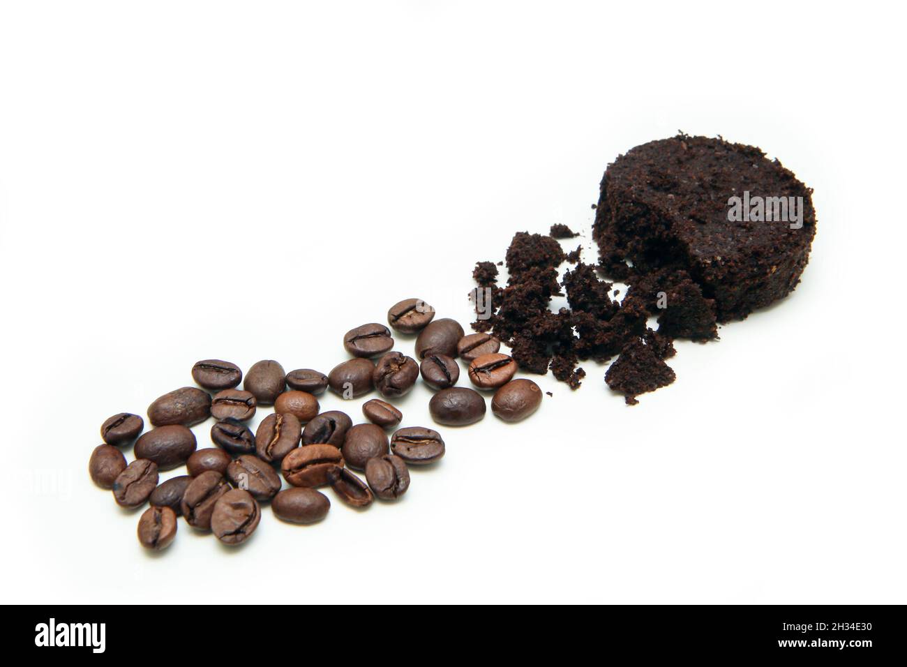 La capsula del caffè usato macina insieme ad una piccola pila di chicchi di caffè torrefatti che dimostrano il processo di macinazione del caffè. Foto Stock