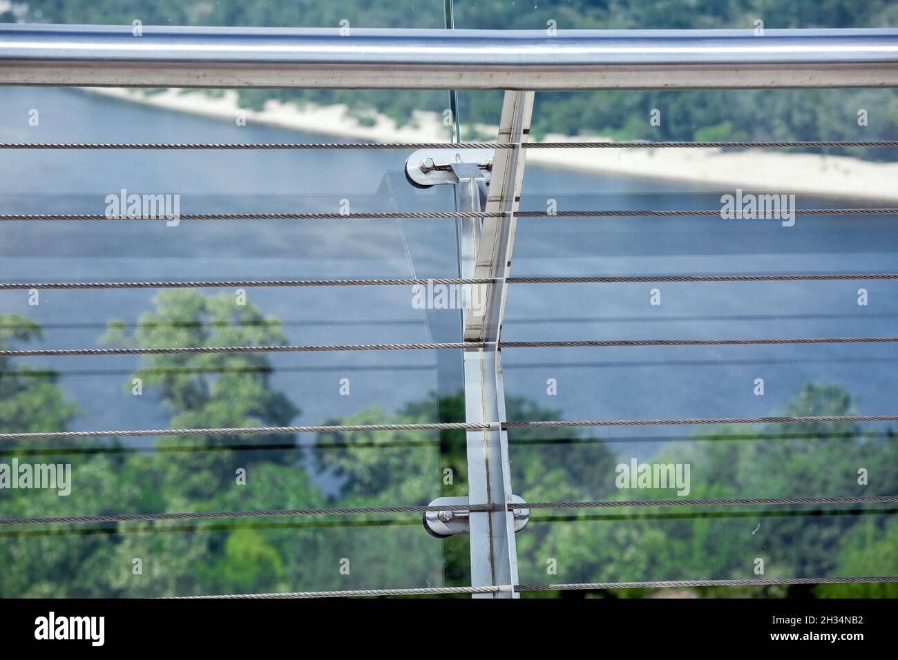 cinghia di bloccaggio in acciaio e vite di dettaglio del sistema di morsetti su ponte di vetro con tensionatori costruzione ingegneristica tenditore in acciaio inox su backgroun Foto Stock
