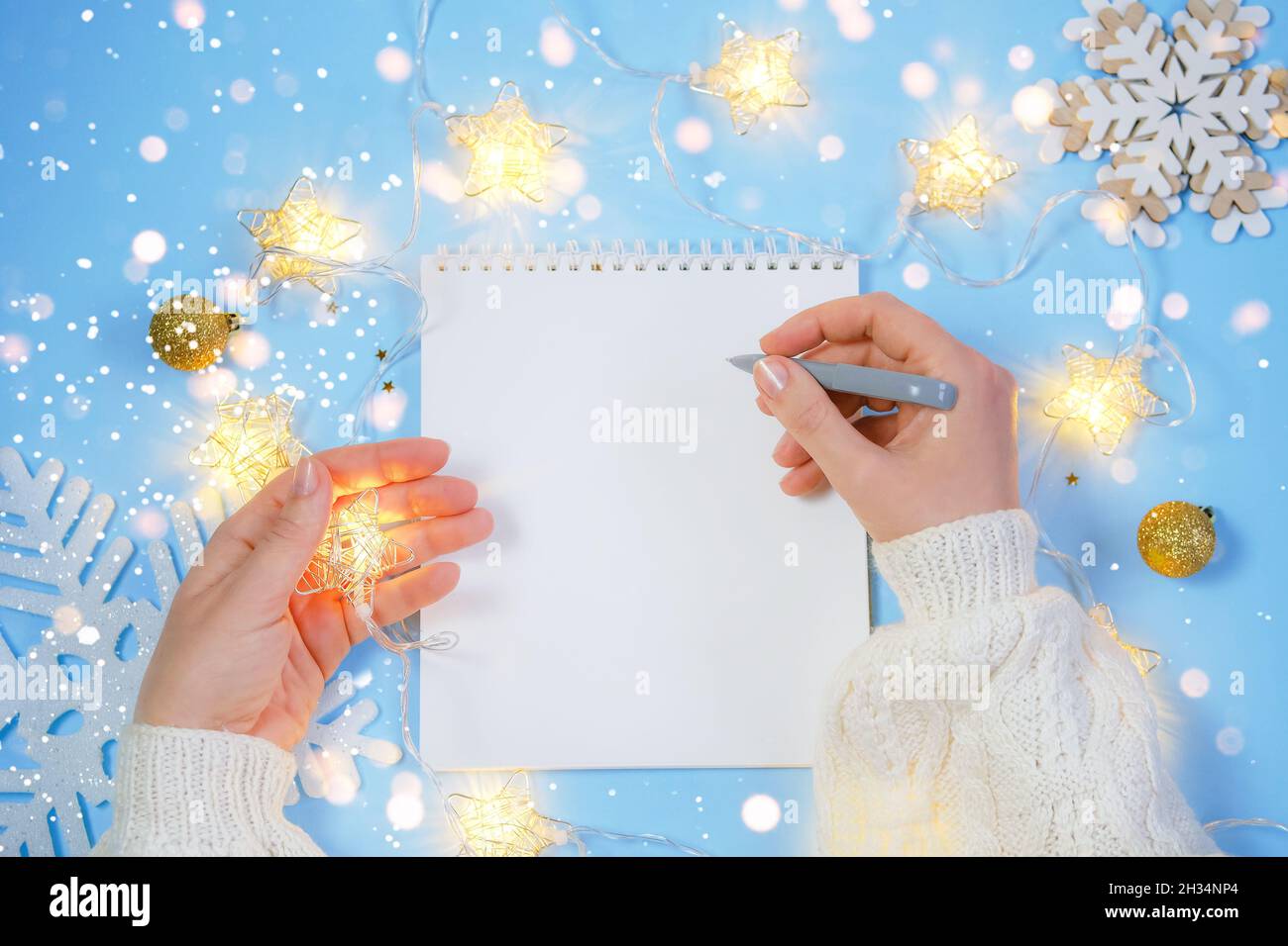 Le mani della donna scrivono in foglio bianco i piani di nuovo anno. Foto Stock