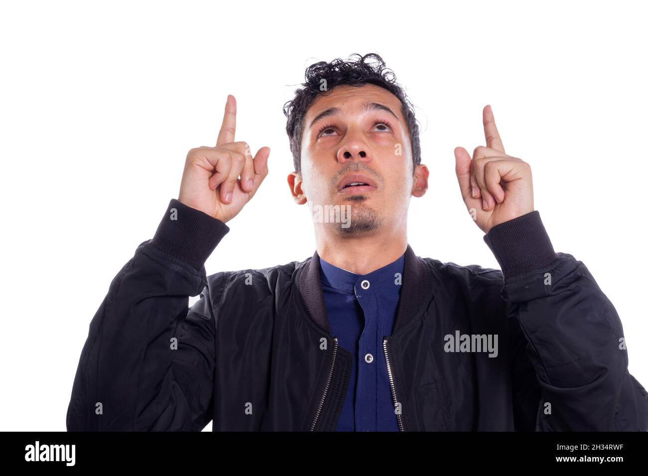 Uomo che punta con entrambe le mani, sfondo bianco. Giovane adulto Latino giovane uomo in cerca. Foto Stock