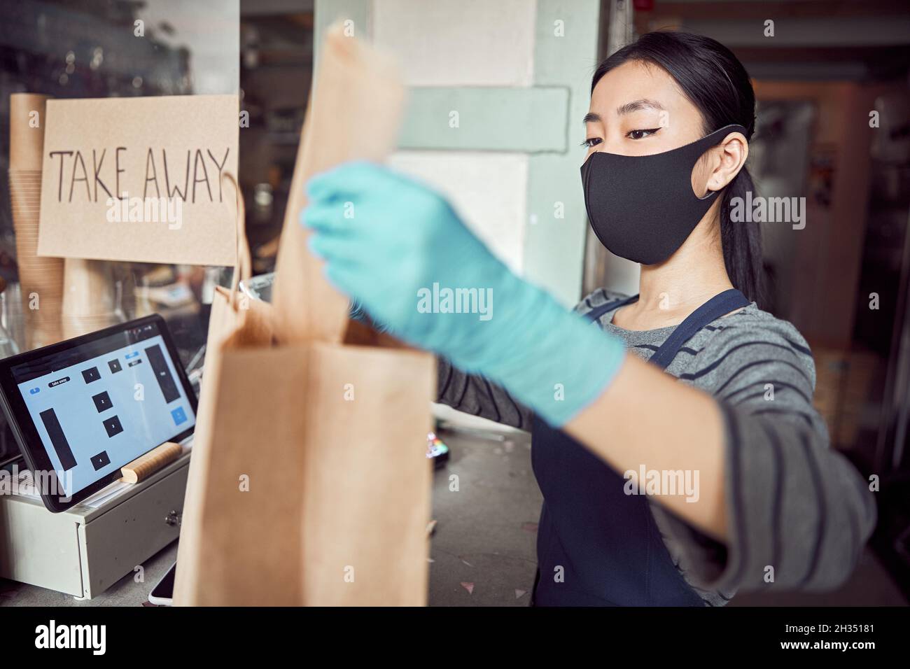 Cameriera asiatica che lavora con gli ordini di takeaway all'interno Foto Stock