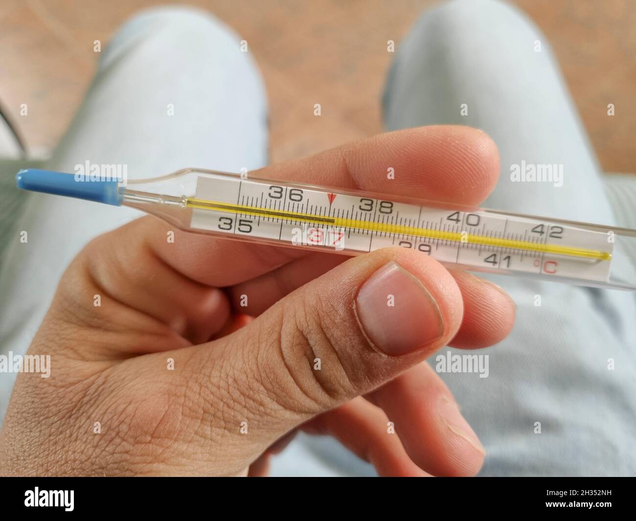 Uomo tenere un termometro di febbre da mercurio dopo la misurazione, coronavirus covid19 pandemica Foto Stock