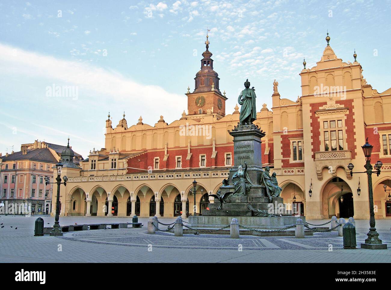 Un monumento in bronzo di Adam Mickiewicz, prolifico poeta romantico, si trova sulla piazza principale del mercato di fronte al salone dei tessuti nella città vecchia di Cracovia, in Polonia. Il monumento fu originariamente inaugurato nel 1898 e fu parzialmente distrutto dai nazisti nel 1940. Dopo essere stato trovato ad Amburgo, in Germania, il monumento in bronzo fu ricostruito e riportato al suo piedistallo nella piazza principale del mercato di Cracovia. La piazza è la più grande piazza medievale d'Europa con la sala dei tessuti in stile rinascimentale al centro. Cracovia fu l'antica capitale della Polonia fino a quando non fu trasferita a Varsavia nel 1945. Foto Stock