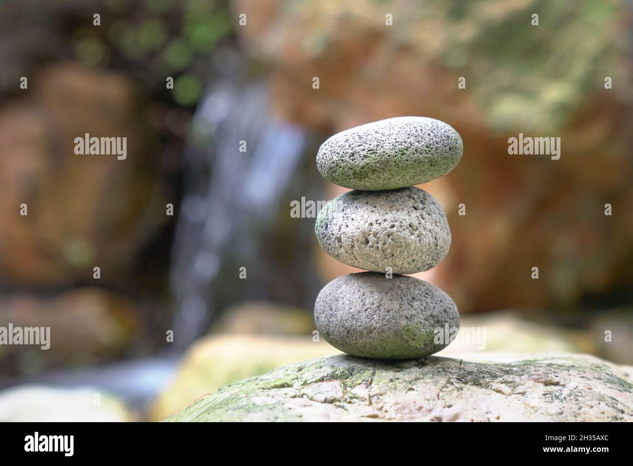Pietre impilate l'una sull'altra con mini cascata sullo sfondo. Equilibrio, zen e concetto di armonia. Foto Stock