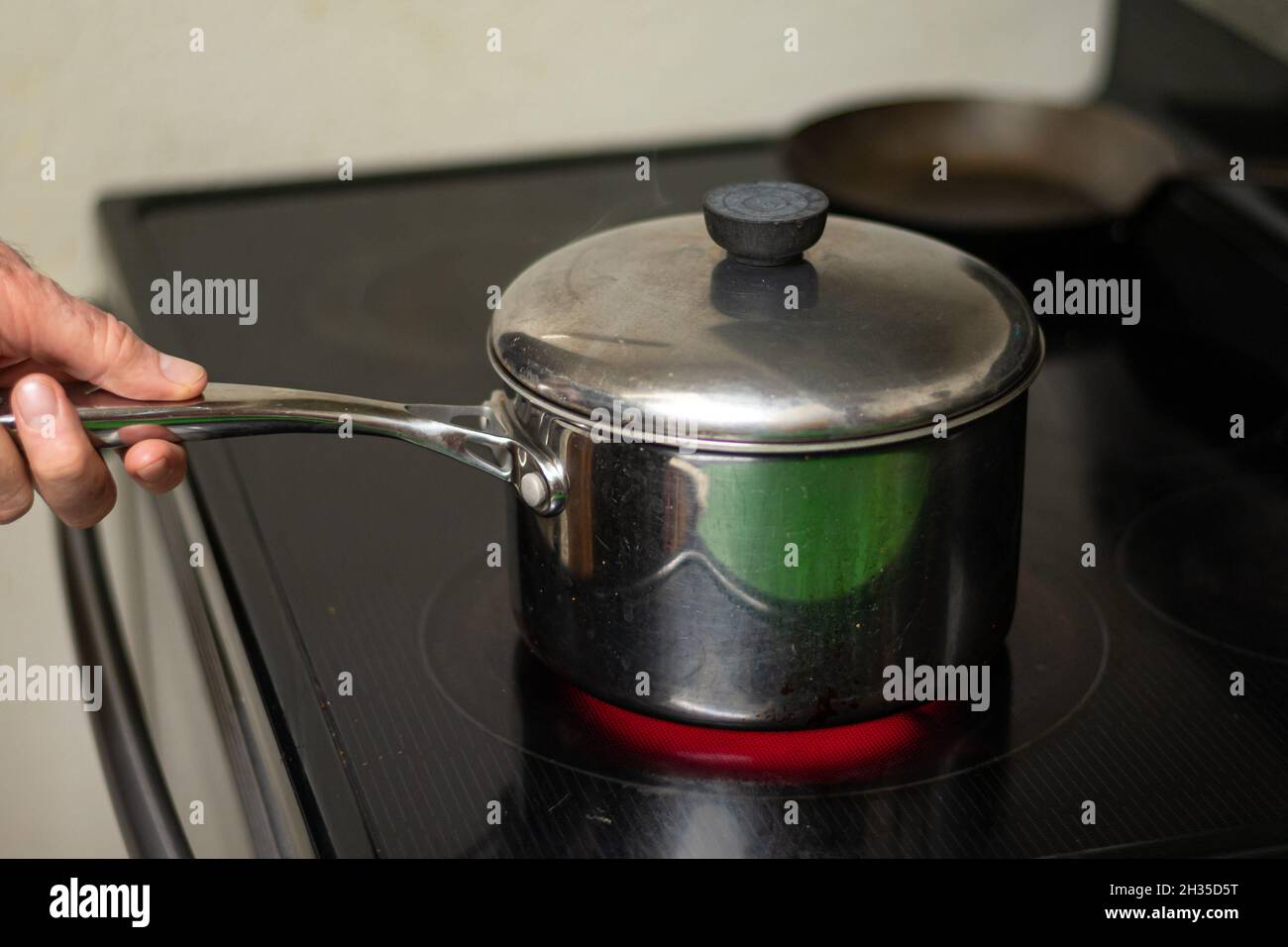 Manico di acciaio inossidabile su stufa a induzione Foto Stock