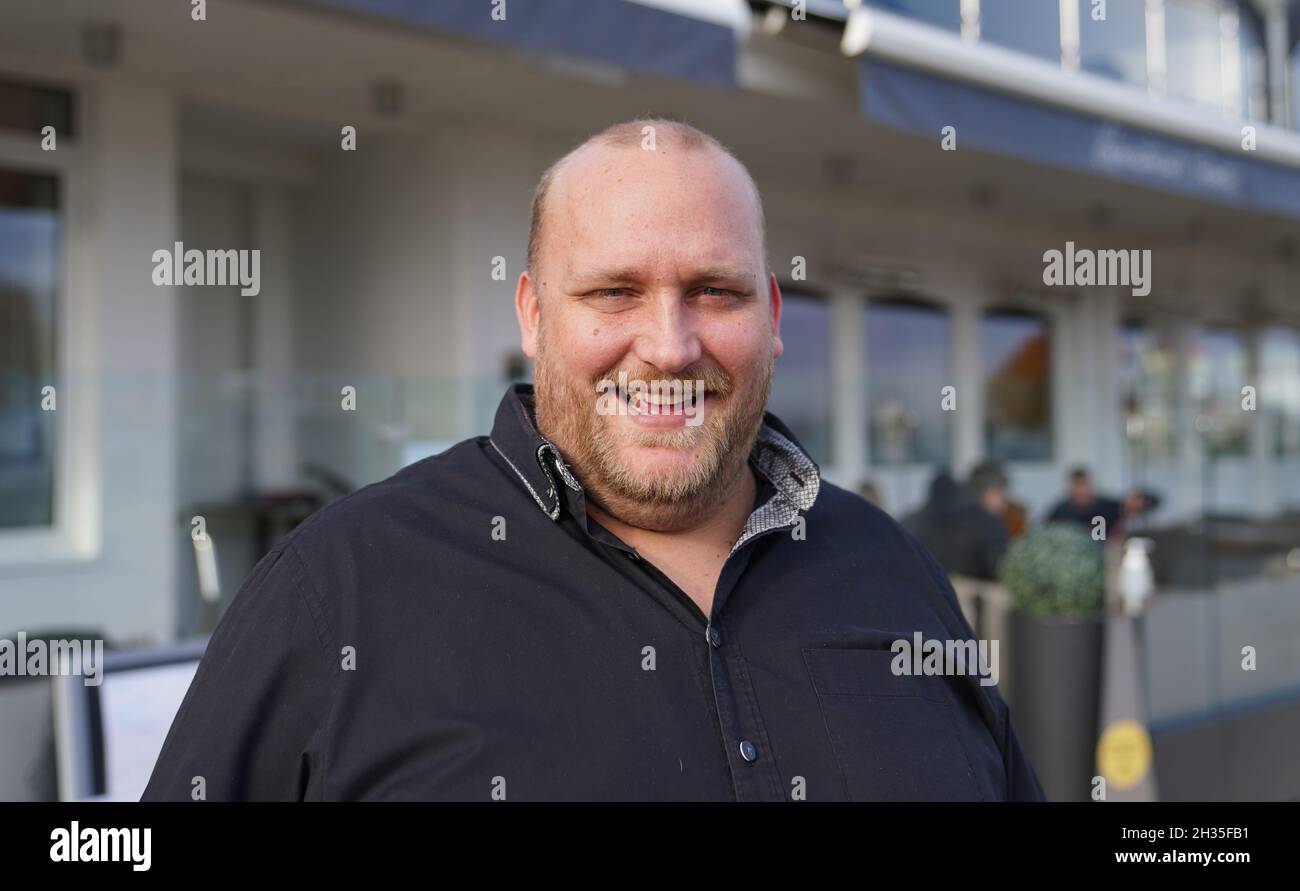 25 ottobre 2021, Schleswig-Holstein, Grömitz: Il custode Tim Bornewasser si trova di fronte al suo ristorante Hafenrestaurant. Sta diventando sempre più difficile per il ristorante sul Mar Baltico trovare personale. Ecco perché Bornewasser ora si affida alla tecnologia moderna. Il robot di servizio 'Bella' supporta il personale di assistenza. (A dpa: 'Supporto per il personale di servizio - Robot 'Bella' serve il cibo ') Foto: Marcus Brandt/dpa Foto Stock