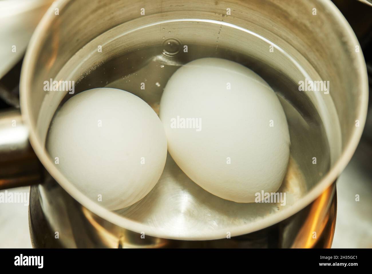 Le uova di pollo vengono bollite in pentola su una stufa a gas. Foto Stock