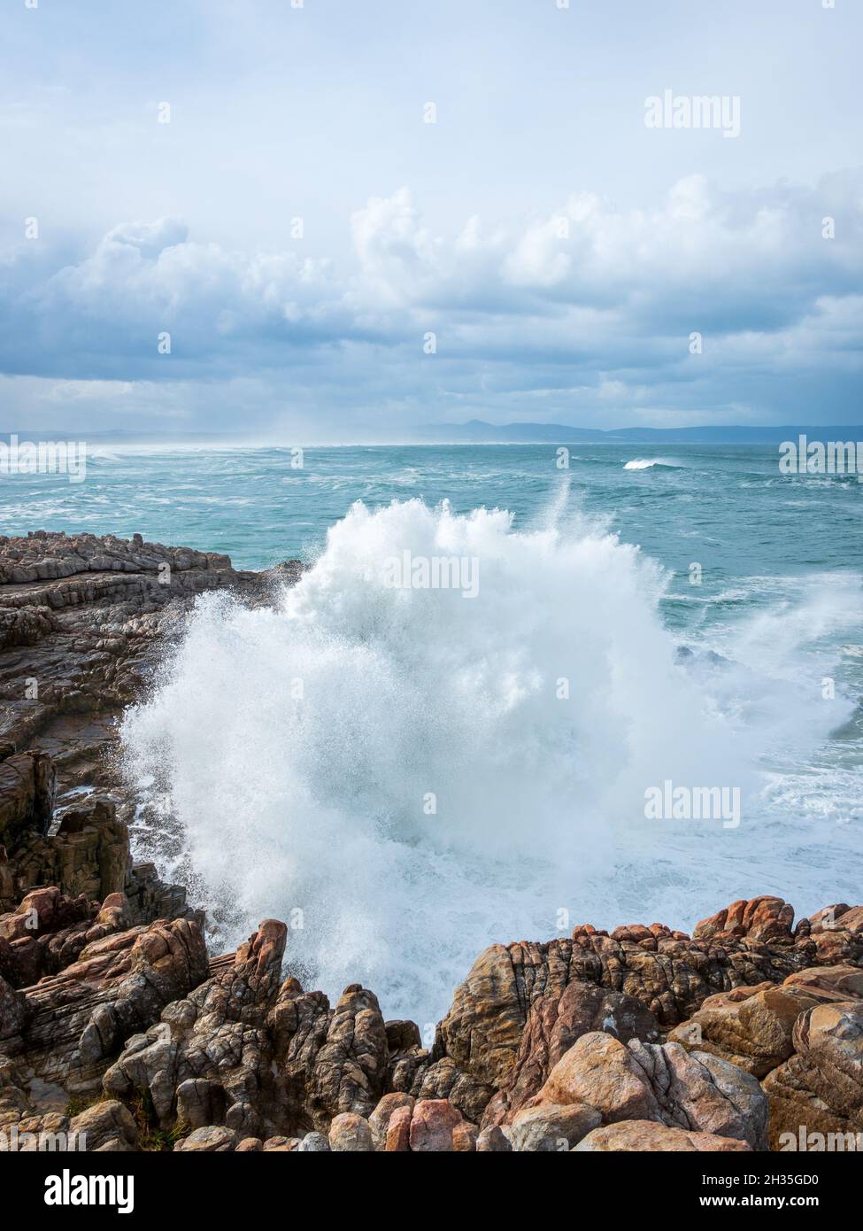 Enormi onde si infrangono su una costa rocciosa sotto un cielo strapiombo. Sievers Point (Sieverspunt) Hermanus. Whale Coast. Overberg. Capo Occidentale. Sud Afri Foto Stock