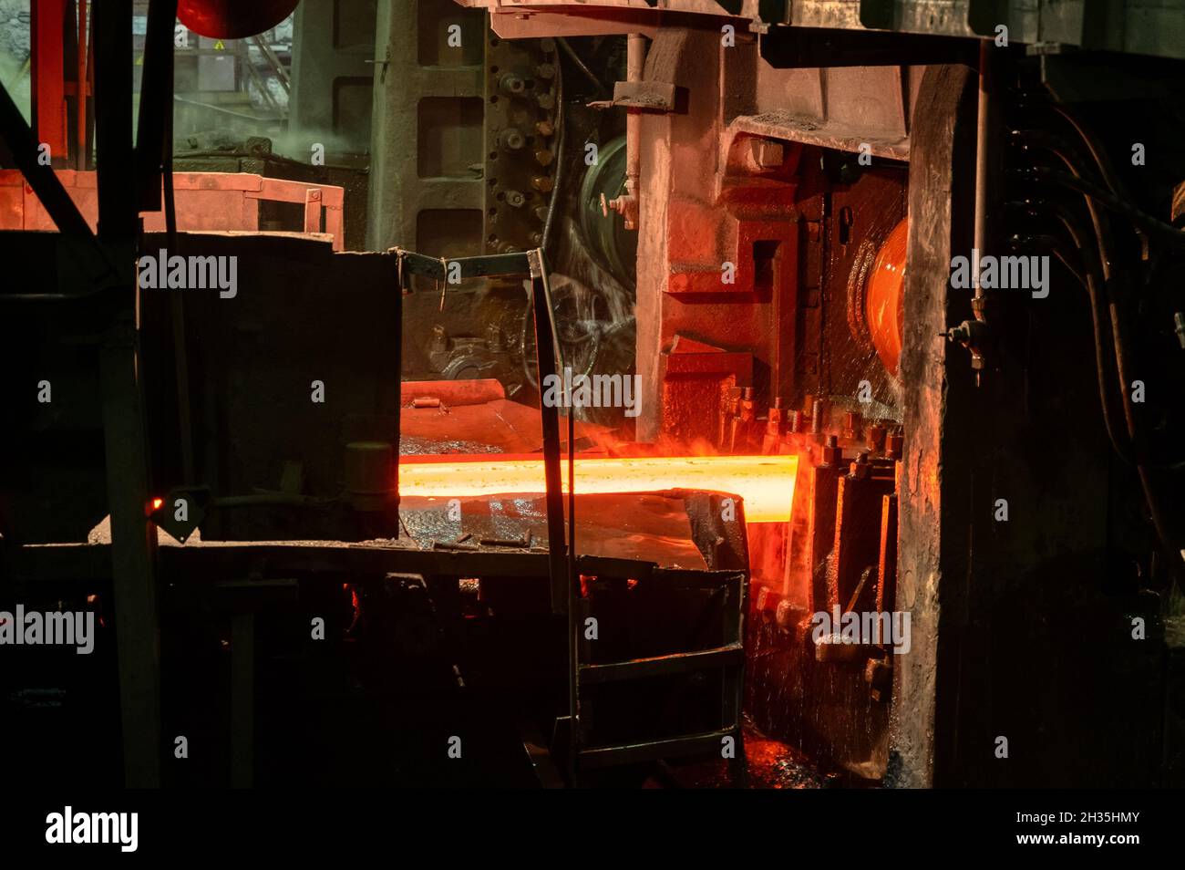 Il laminatoio in funzione. Il metallo caldo viene fatto rotolare attraverso rulli raffreddati Foto Stock