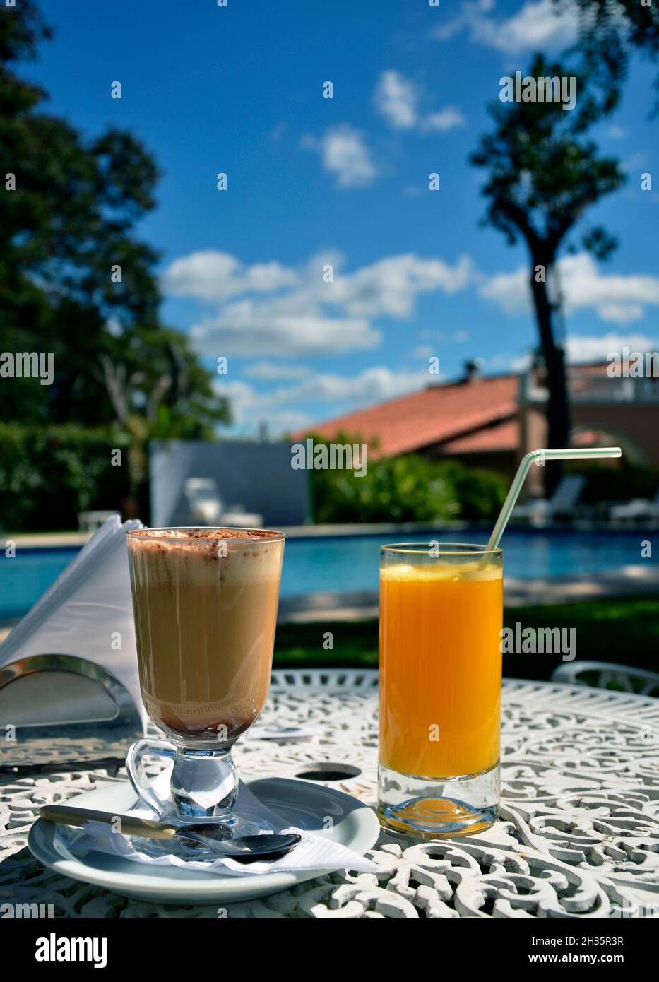 Colazione vicino alla piscina, con cappuccino e succo d'arancia. Petit déjeuner au bord de la piscine. Foto Stock