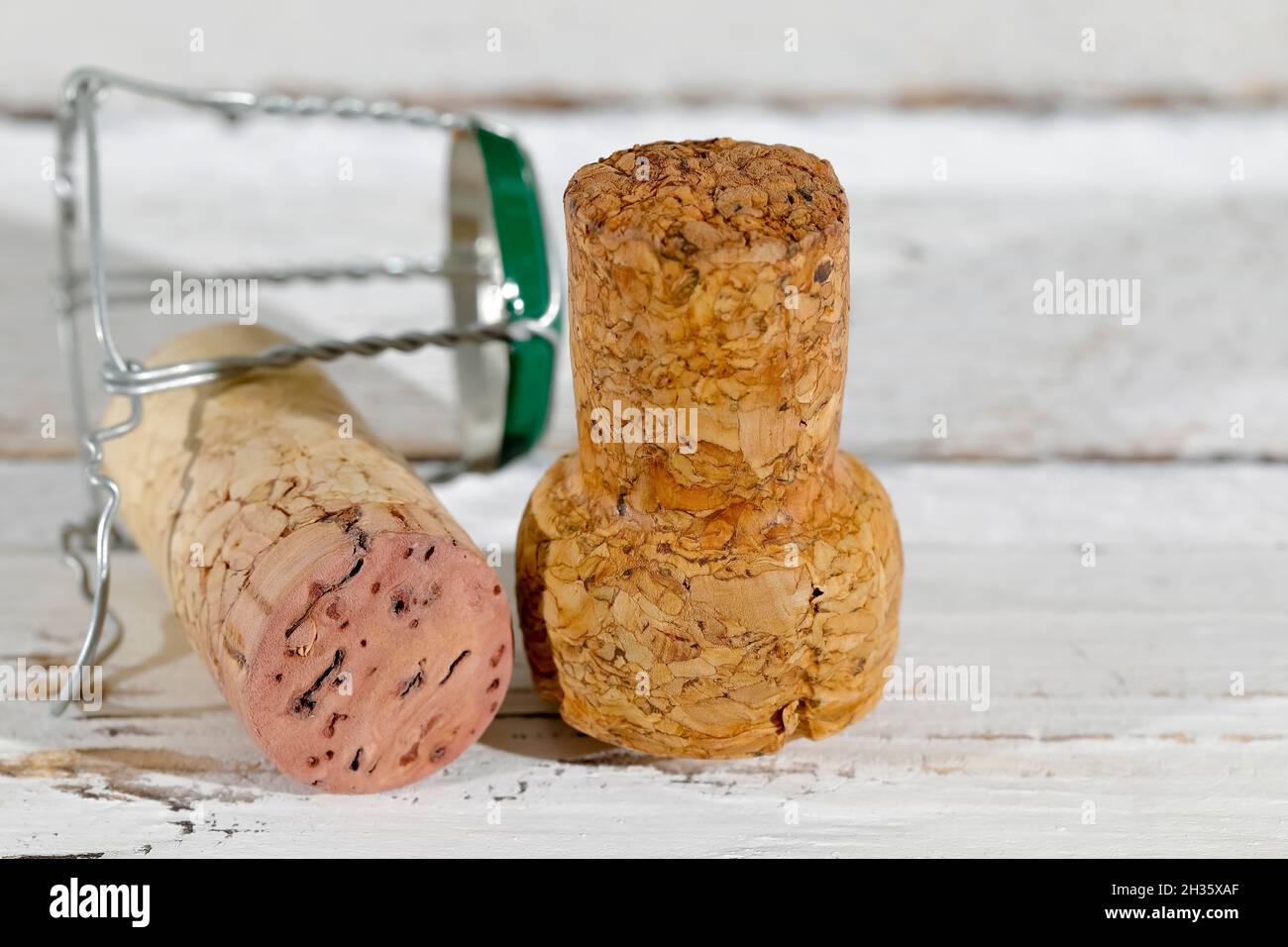 I tappi di sughero di uno spumante sono mostrati su una superficie di una tavola bianca, c'è anche un sughero di un vino rosso. Foto Stock