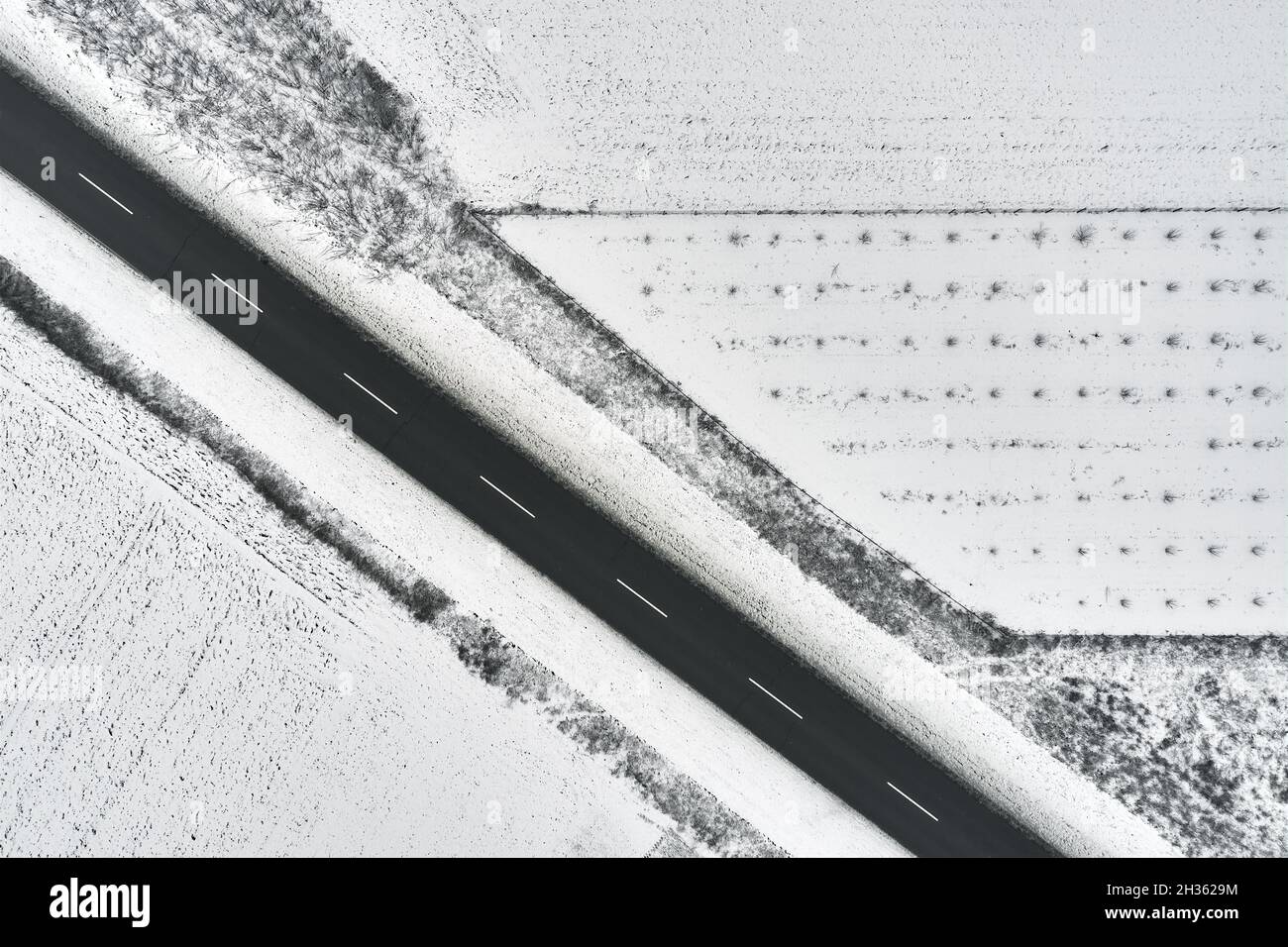 Foto aerea dall'alto della strada vuota attraverso la campagna in inverno, composizione astratta minima Foto Stock