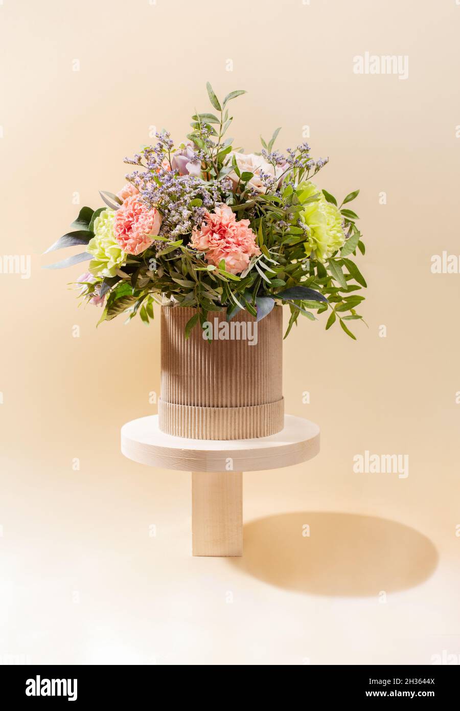 Composizione eco-compatibile monocromatica con bouquet di fiori su supporti in legno di forme diverse sul beige. Minimo moderno layout festivo di Europa Foto Stock