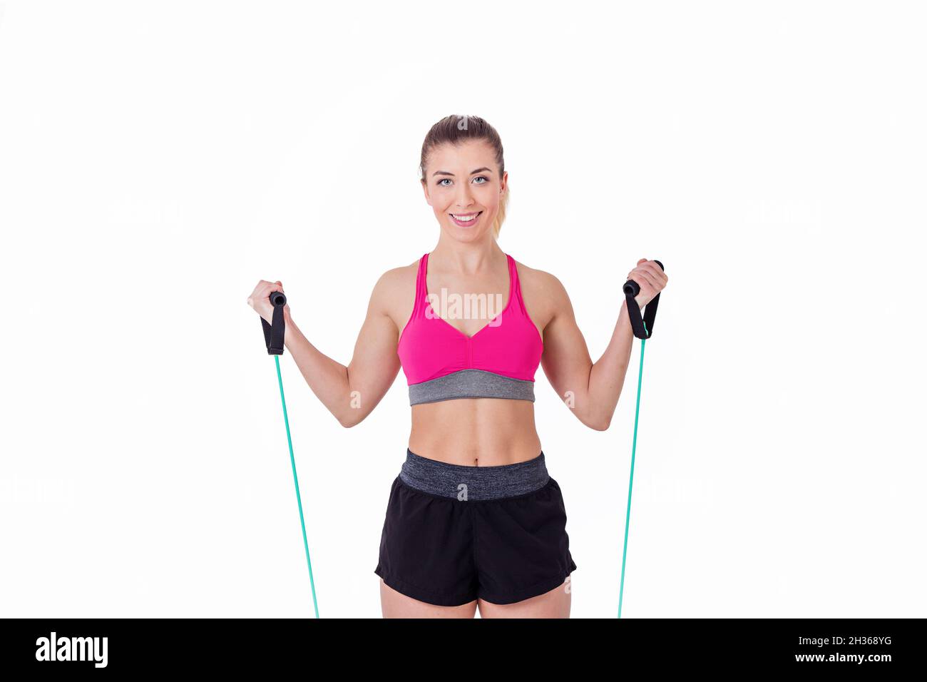 Giovane donna che si esercita con fasce elastiche che guardano la fotocamera su sfondo bianco. Foto Stock