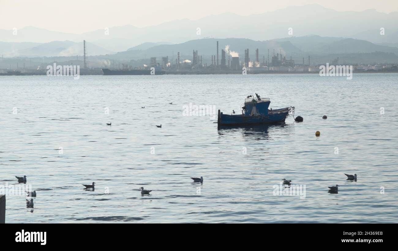 Gabbiani e piccola barca da pesca nel porto turistico di Milazzo in Sicilia sulla costa di fronte alla raffineria petrolifera Foto Stock