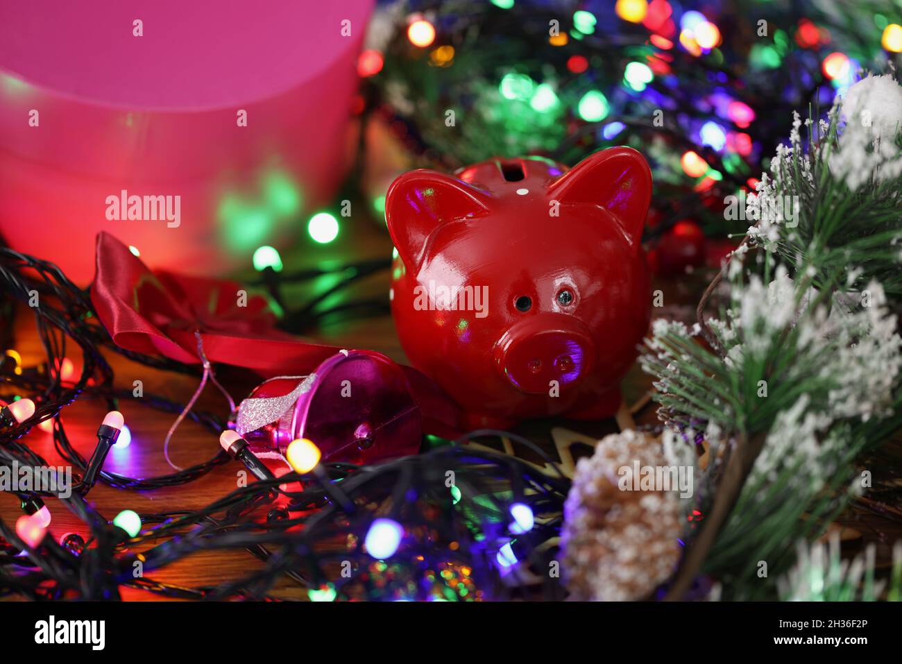 Red Piggy banca in piedi tra brillante lucido anno nuovo garland primo piano Foto Stock