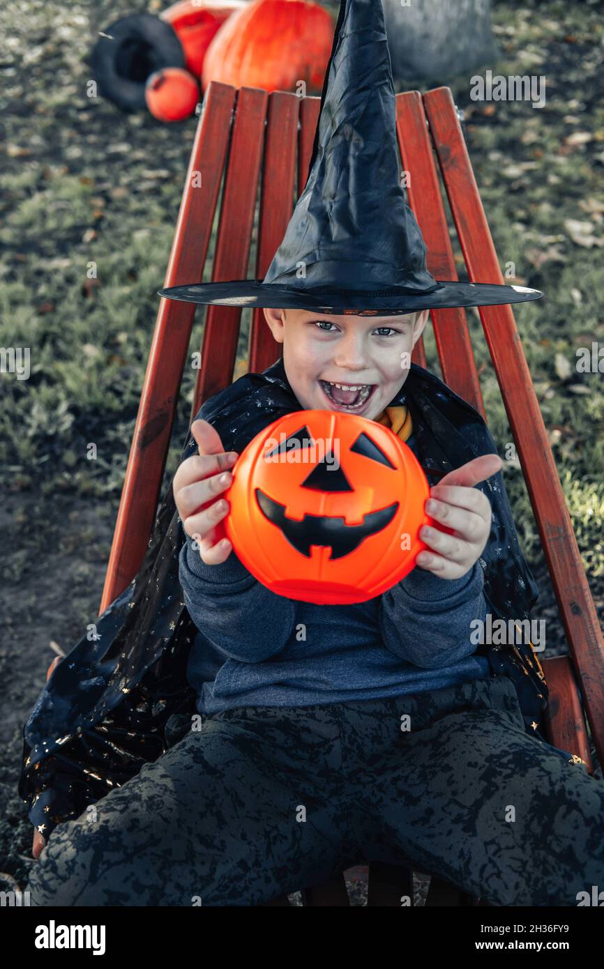 Halloween bambini. Ragazzo carino, bambino che indossa il cappello della strega con secchio arancione di caramelle Jack o Lanterna. Buon Halloween. Foto Stock