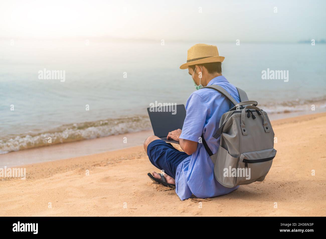 Uomo indossare maschera utilizzando computer portatile sulla spiaggia mare e uomo viaggio vacanza Phuket sandbox Thailandia sono libertà vita finanziaria Foto Stock