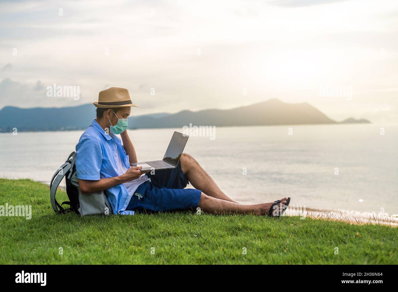 Uomo indossare maschera utilizzando computer portatile sulla spiaggia mare e uomo viaggio vacanza Phuket sandbox Thailandia sono libertà vita finanziaria Foto Stock