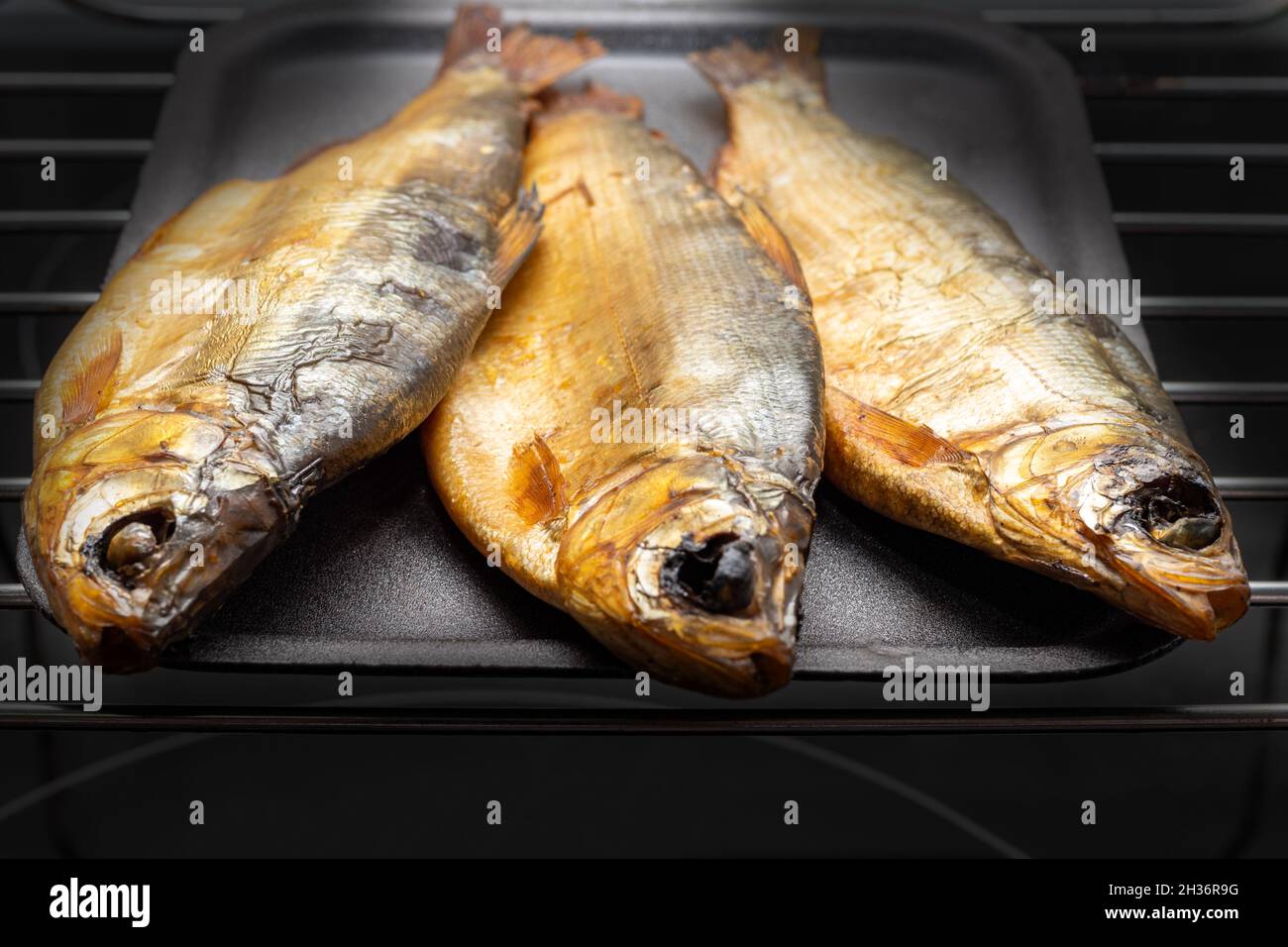 Appetitoso pesce fresco affumicato pelato su un piatto nero su sfondo scuro. Fumo fatto in casa. Cibo delizioso e sano. Snack alla birra Foto Stock