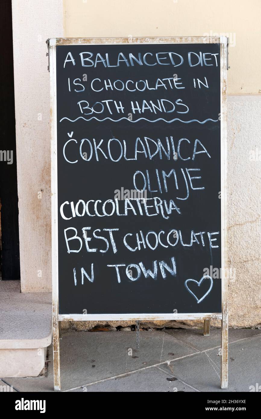 Un divertente segno fuori da un negozio di cioccolato a Piran, Slovenia, che dice che una dieta equilibrata è cioccolato in entrambe le mani. Foto Stock