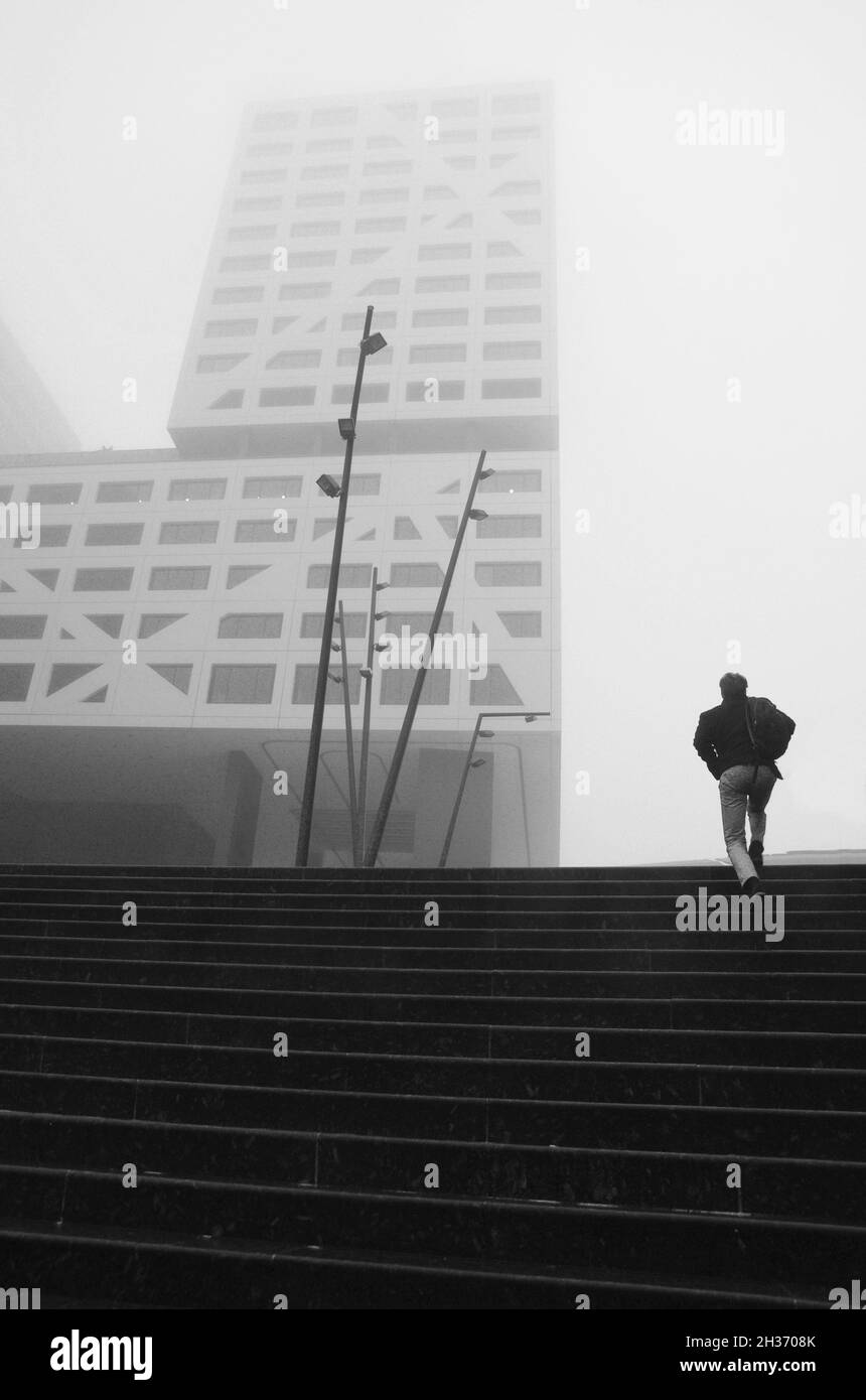 Un uomo che sale le scale andando a lavorare in ufficio in una mattina nebbiosa Foto Stock