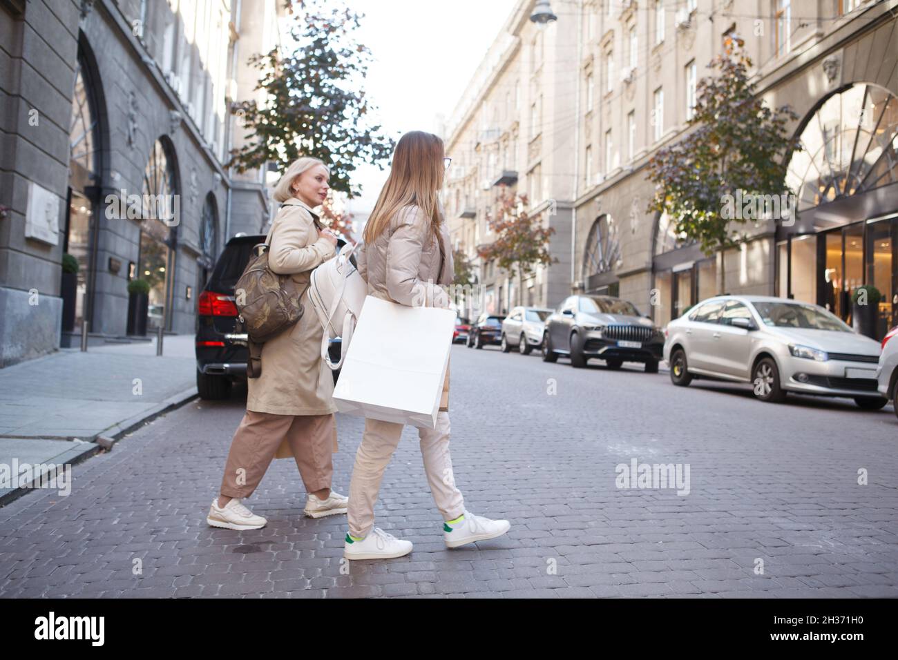 Foto a tutta lunghezza di due donne con borse per lo shopping, attraversando la strada nel centro della città Foto Stock