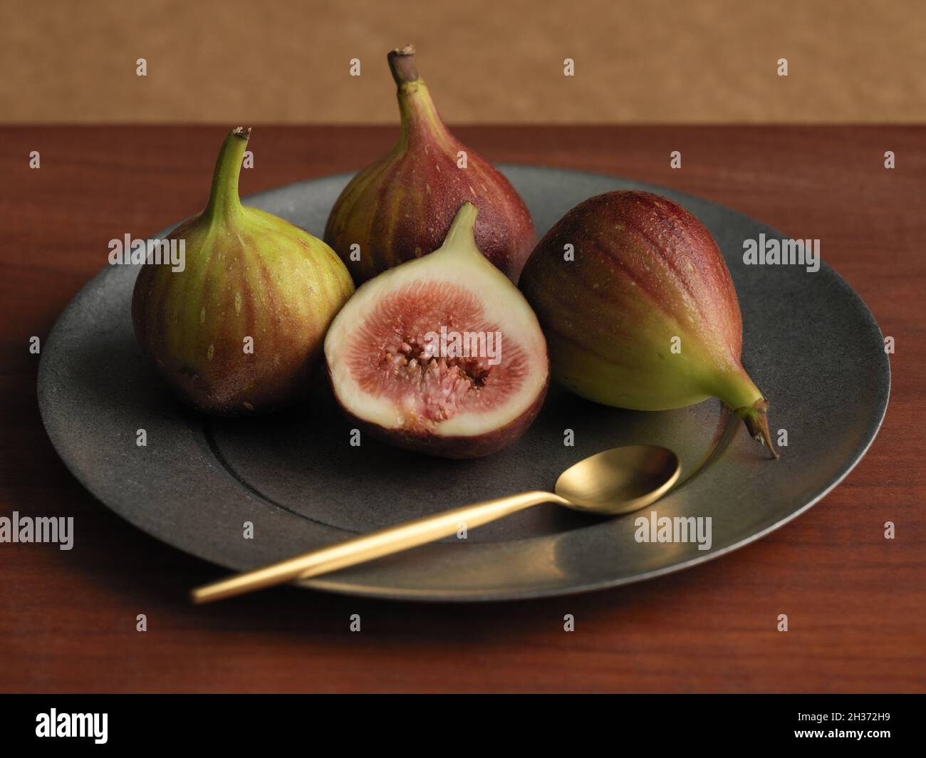 Fig. Su piatto di latta con cucchiaio di ottone Foto Stock