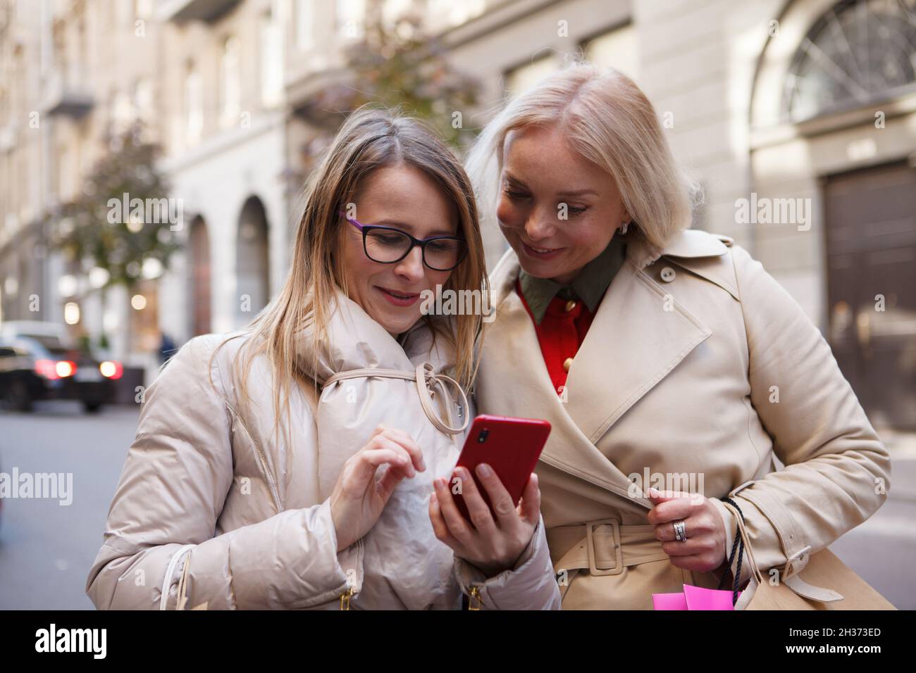 Due donne mature che usano lo smart phone all'aperto insieme Foto Stock