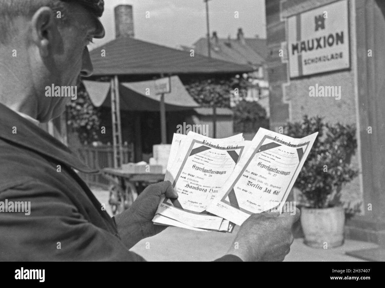 Stationsvorsteher mit Expreßscheinen für den Bahntransport von frischem Obst durch die Deutsche Reichsbahn, Deutschland 1930er Jahre. Capostazione con espresso sotto forma di fogli per la consegna della frutta fresca da Deutsche Reichsbahn, Germania 1930s. Foto Stock