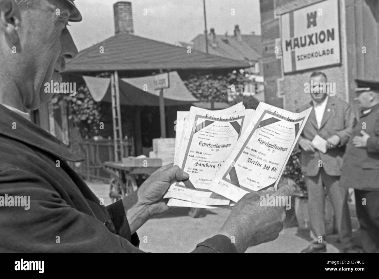 Stationsvorsteher mit Expreßscheinen für den Bahntransport von frischem Obst durch die Deutsche Reichsbahn, Deutschland 1930er Jahre. Capostazione con espresso sotto forma di fogli per la consegna della frutta fresca da Deutsche Reichsbahn, Germania 1930s. Foto Stock