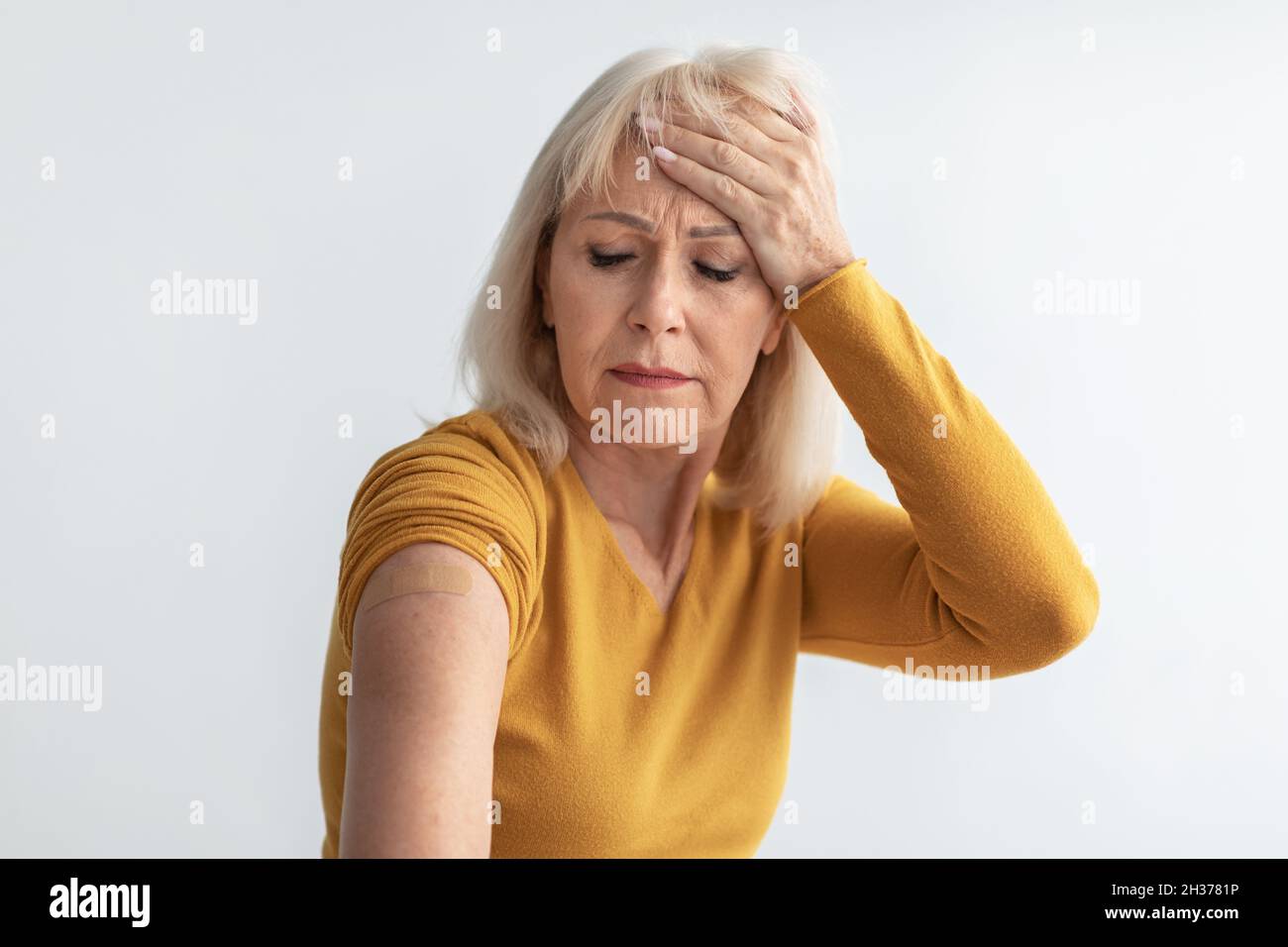 Senior Lady che ha mal di testa dopo la vaccinazione con effetto collaterale, Studio Shot Foto Stock