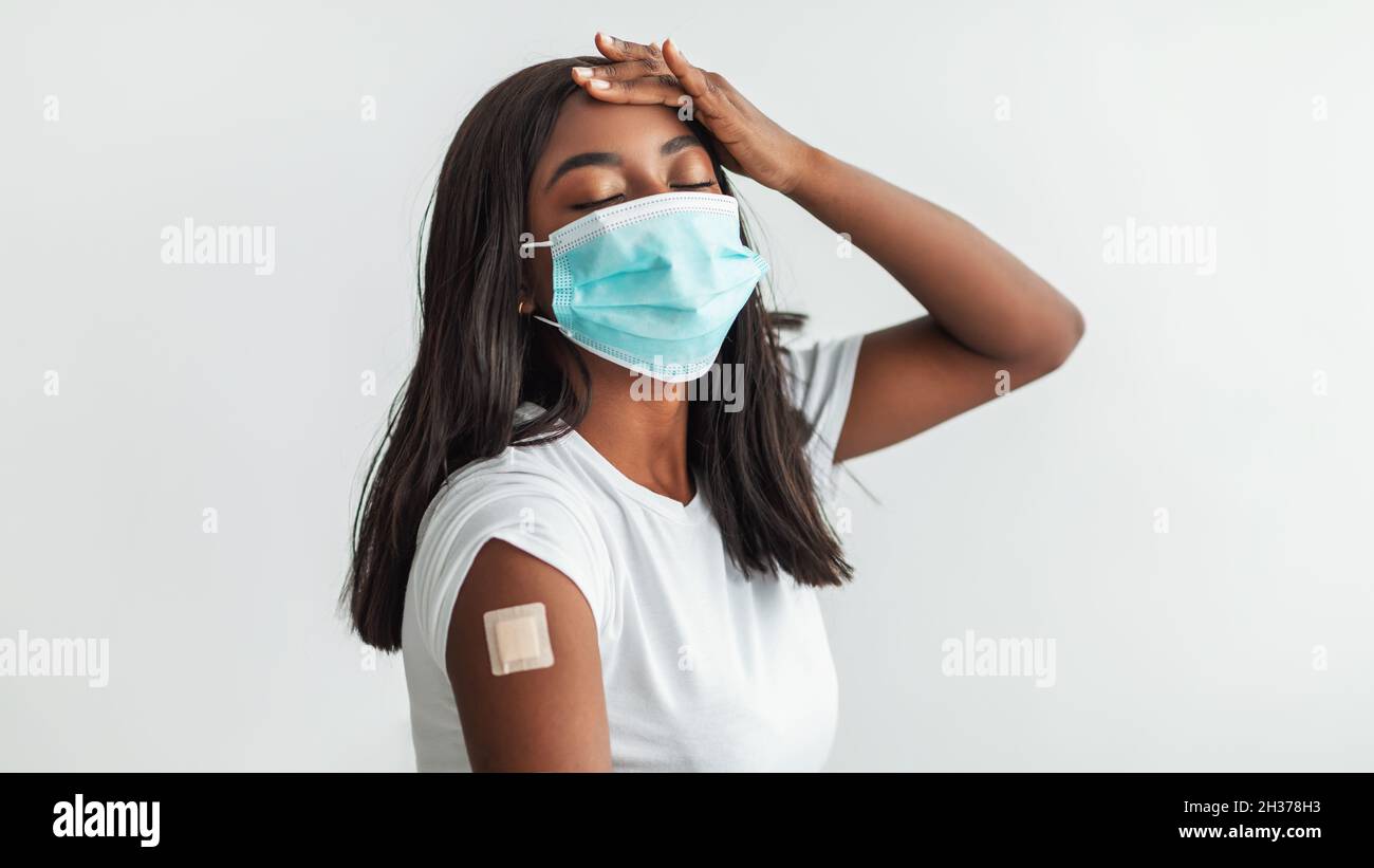 Black Woman in Face Mask che soffre di febbre dopo il vaccino Foto Stock